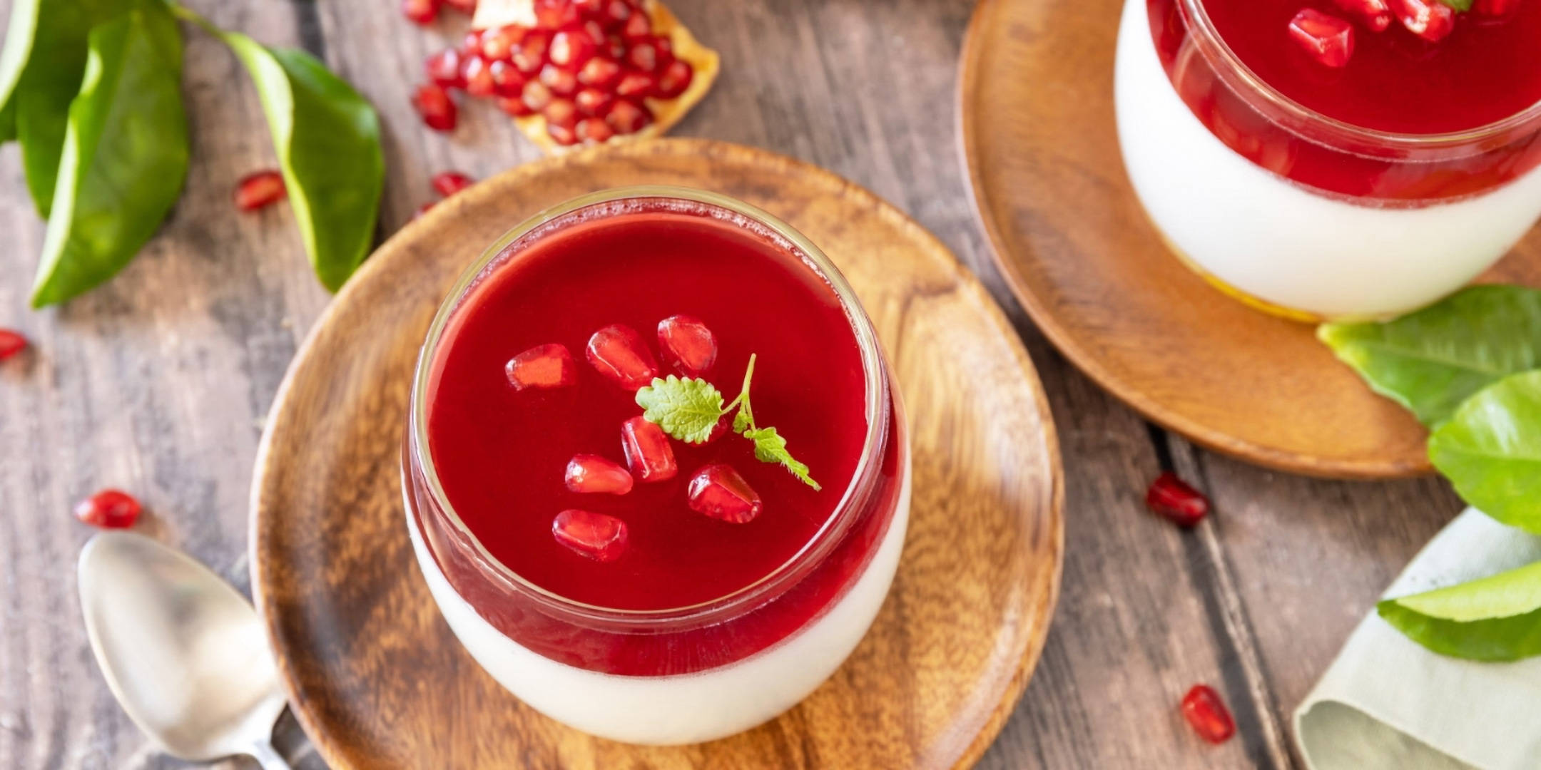 Schichtdessert im Glas mit Granatapfelkernen und Minze.