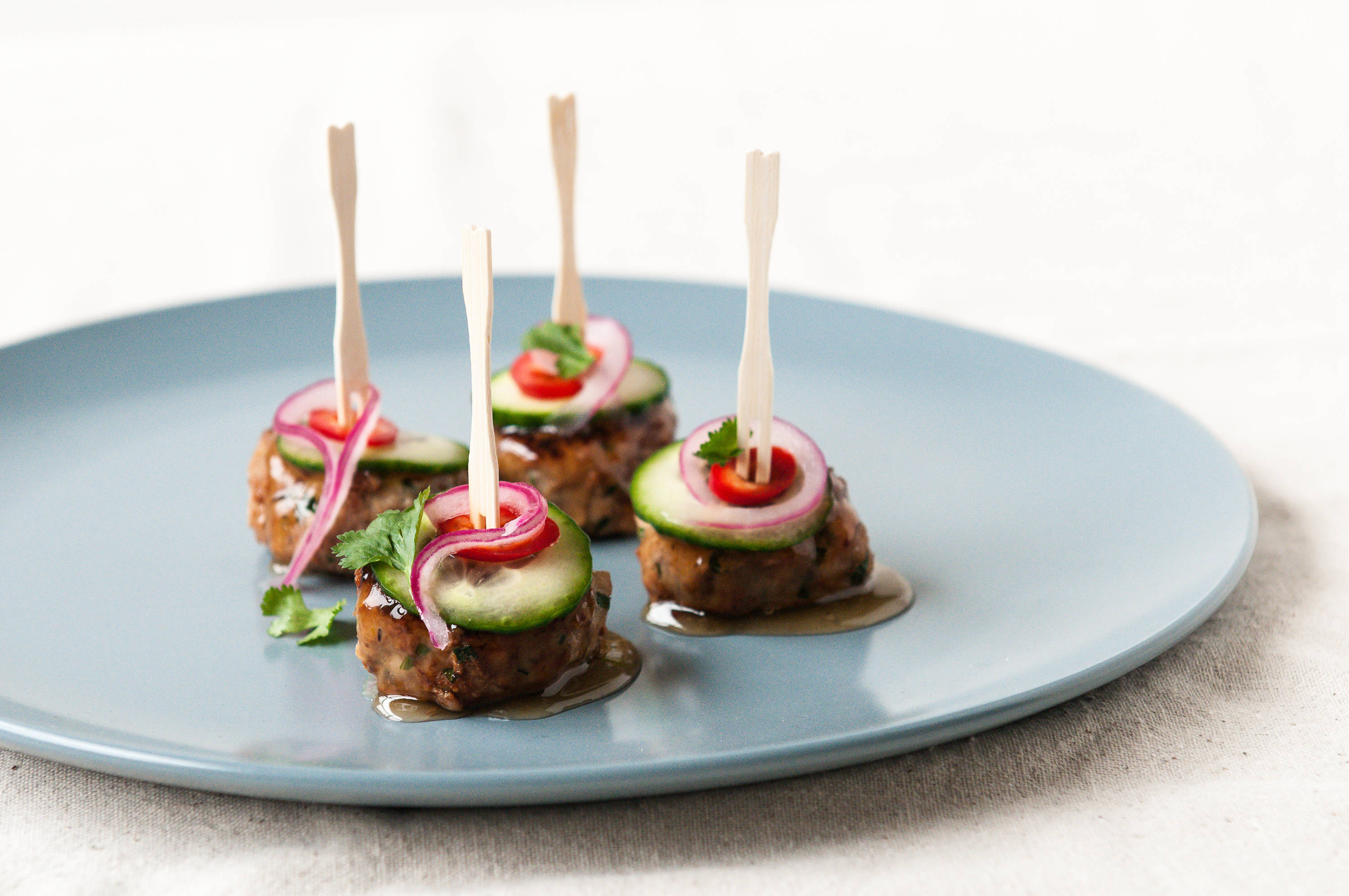 Vier Fingerfood-Spieße mit Gurke, Zwiebel, Chili auf Teller.