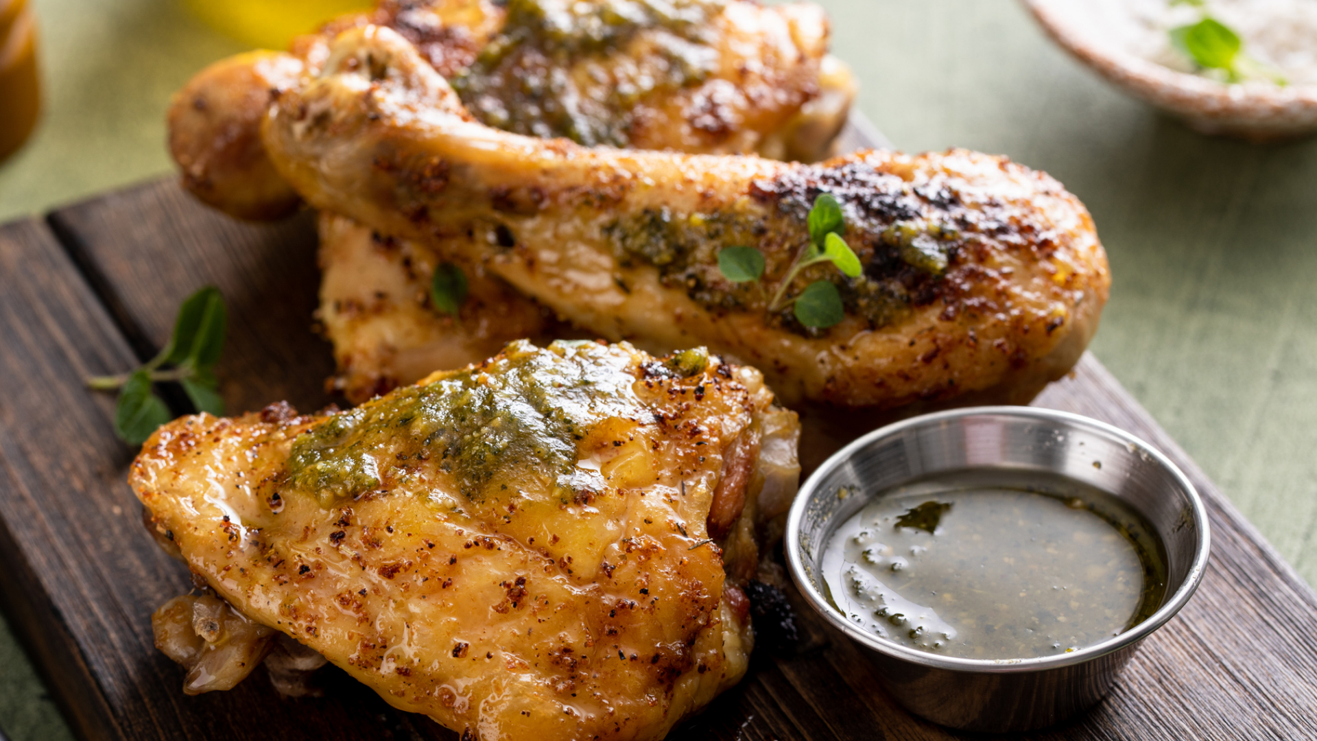 Goldbraunes Hähnchen mit grüner Kräutersauce auf Holzbrett.