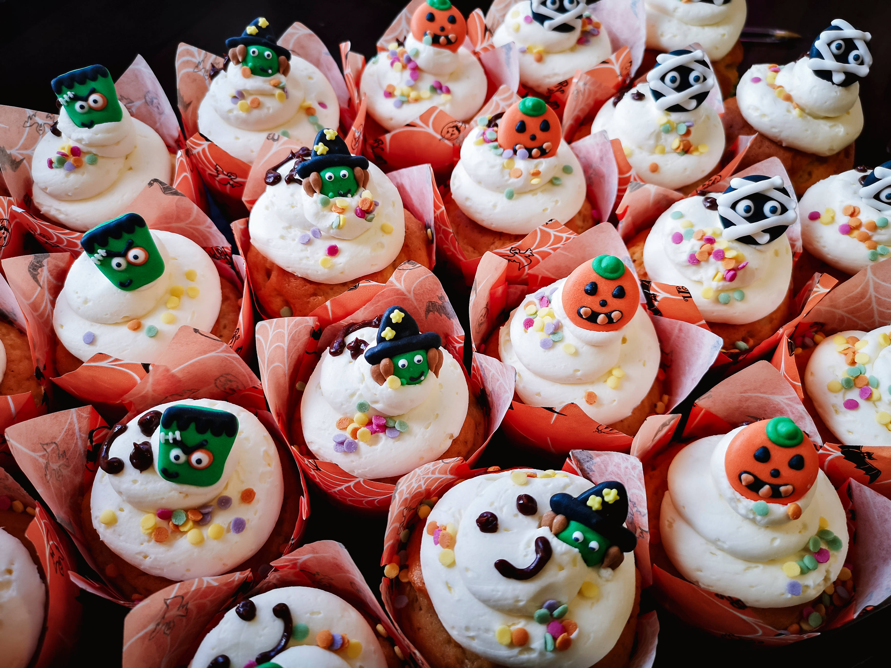Halloween-Cupcakes mit verschiedenen Monster- und Kürbisfiguren.