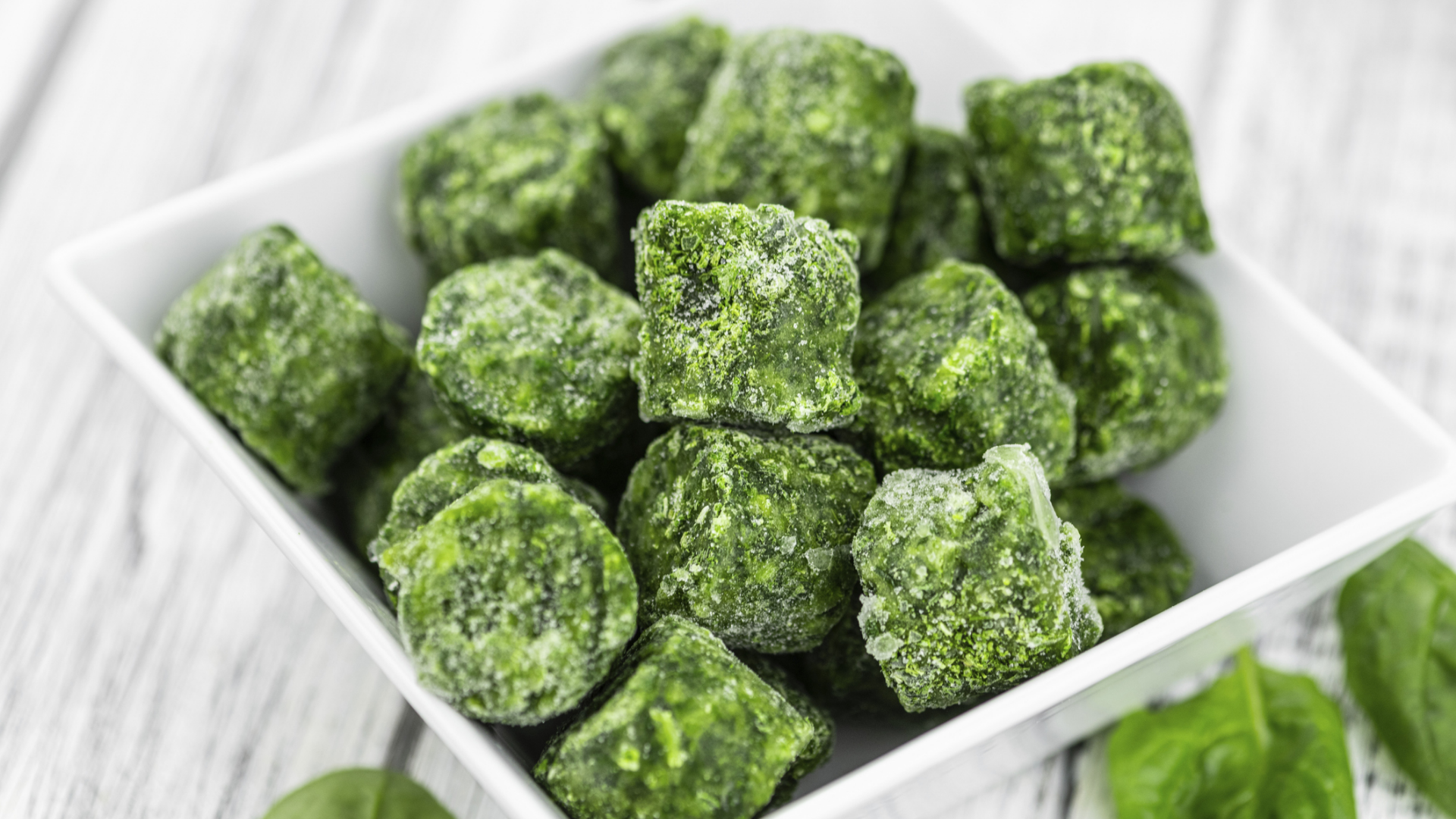 Tiefgekühlter Spinat in Würfelform in einer weißen Schale.