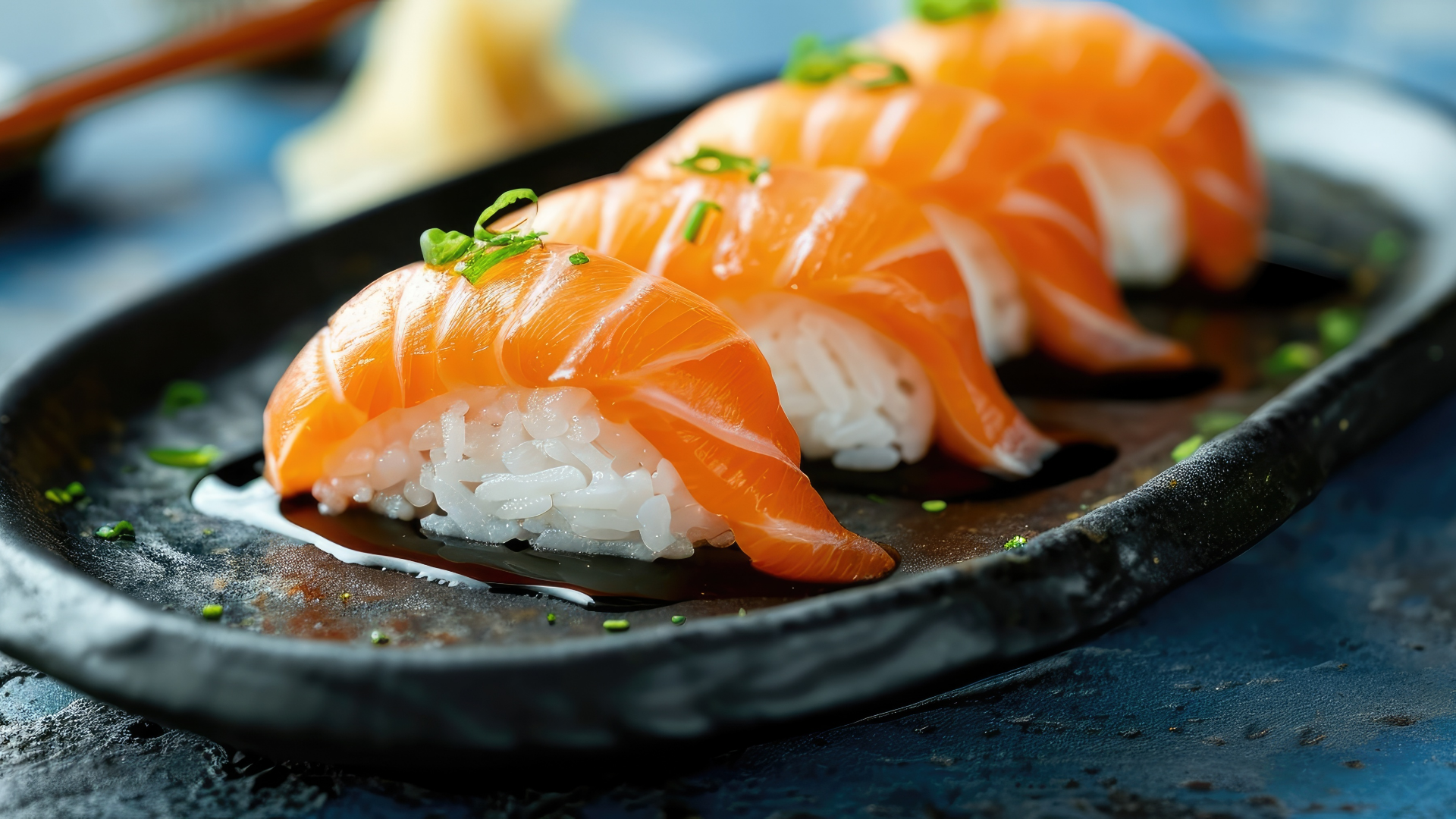Lachs-Nigiri-Sushi auf einem Teller mit Sojasauce und Wasabi.
