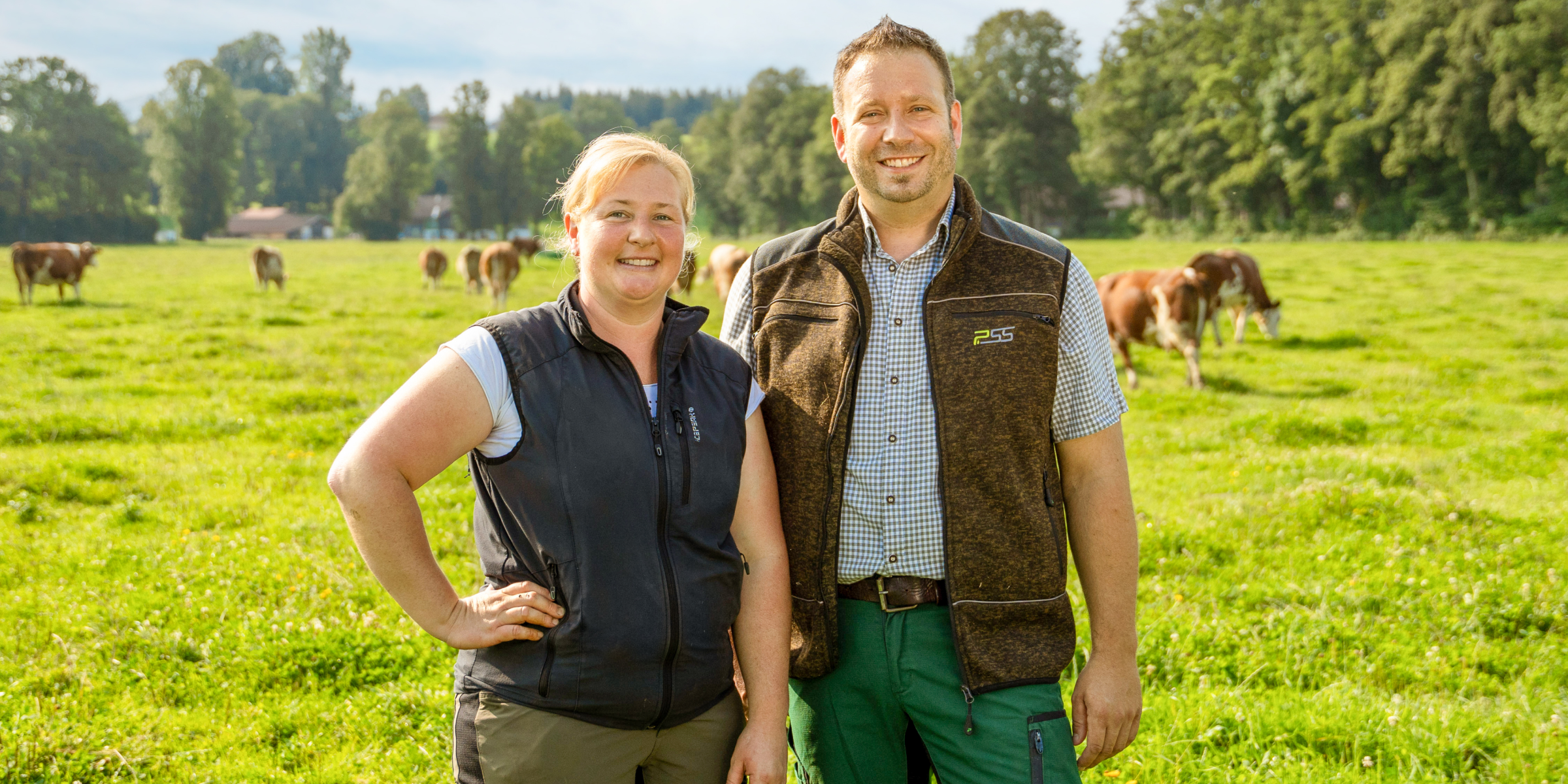 Naturland-Landwirte Herr und Frau Müller vor einer Kuhherde auf der Wiese.