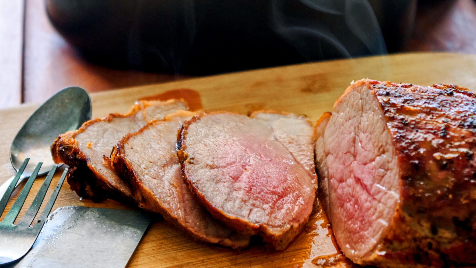 Frisch aufgeschnittener, dampfender Braten auf Holzbrett.