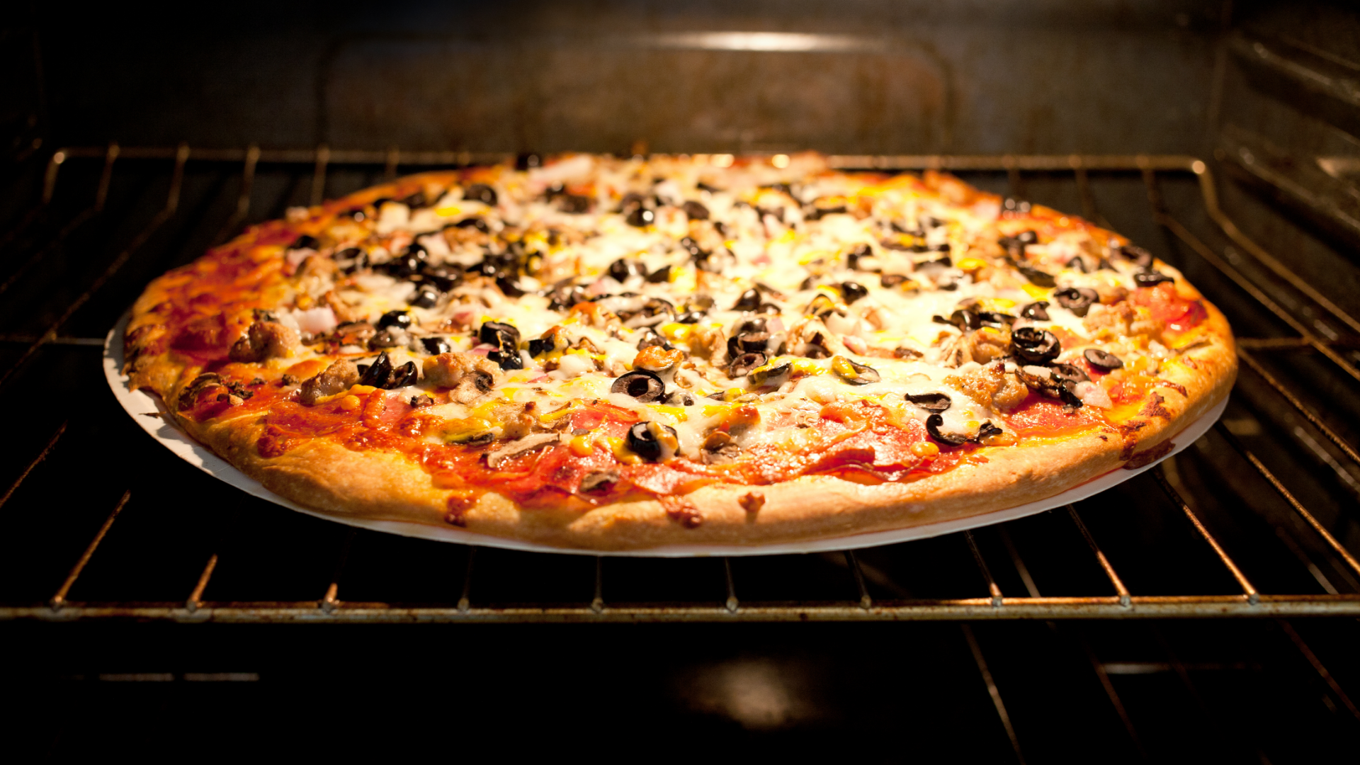 Pizza mit Oliven backt im Ofen.