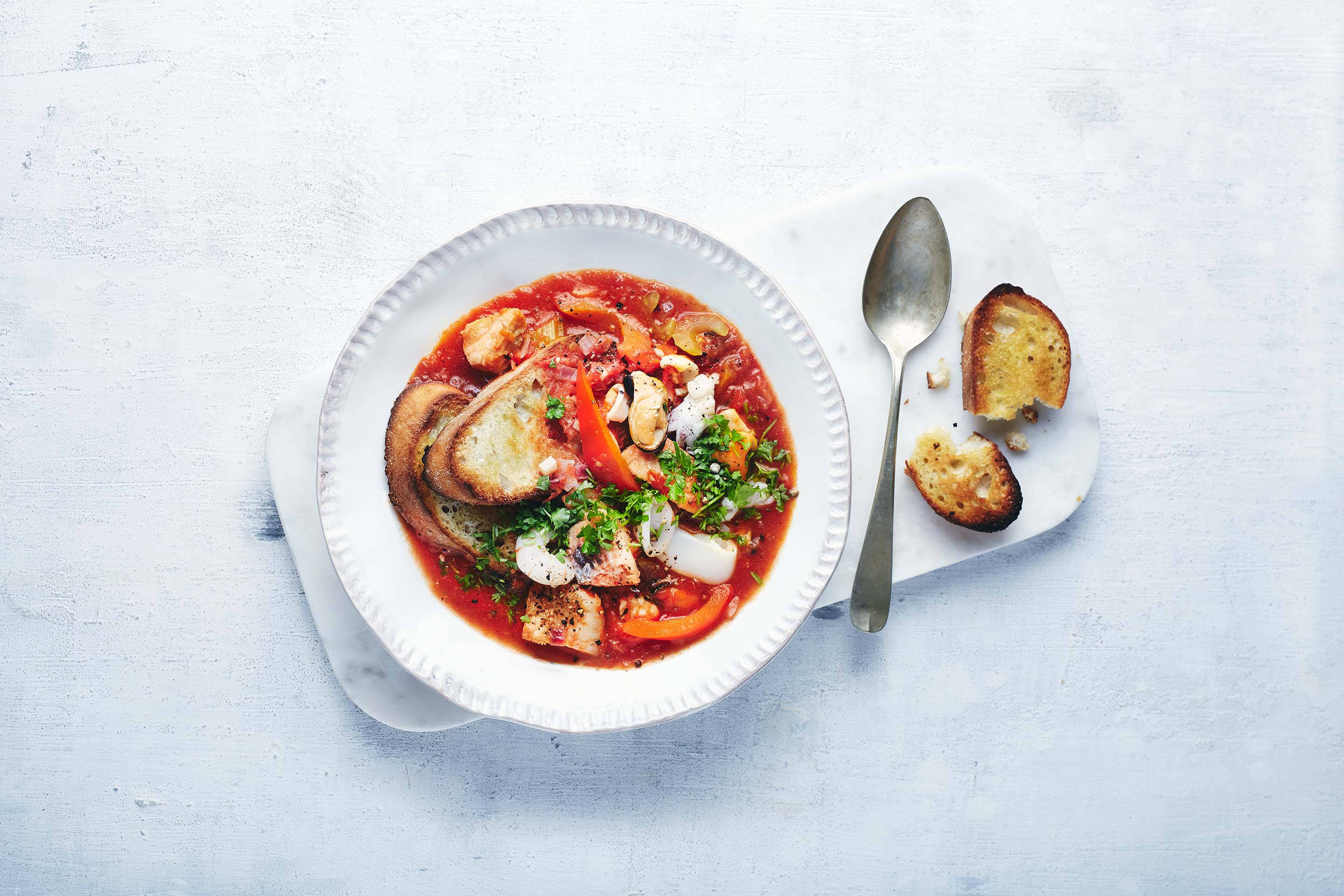 Tomatiger Meeresfrüchteeintopf mit geröstetem Brot.