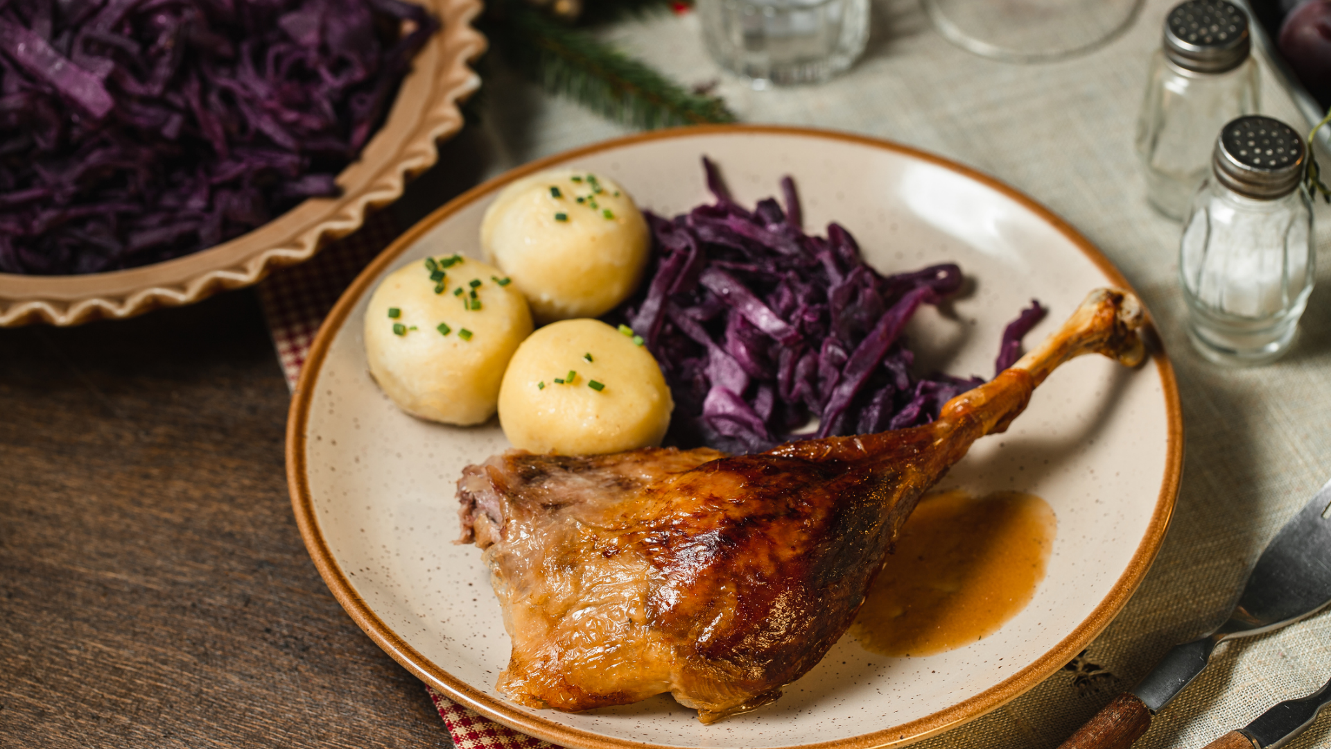 Weihnachtsgans mit Knödeln und Rotkohl auf Teller.
