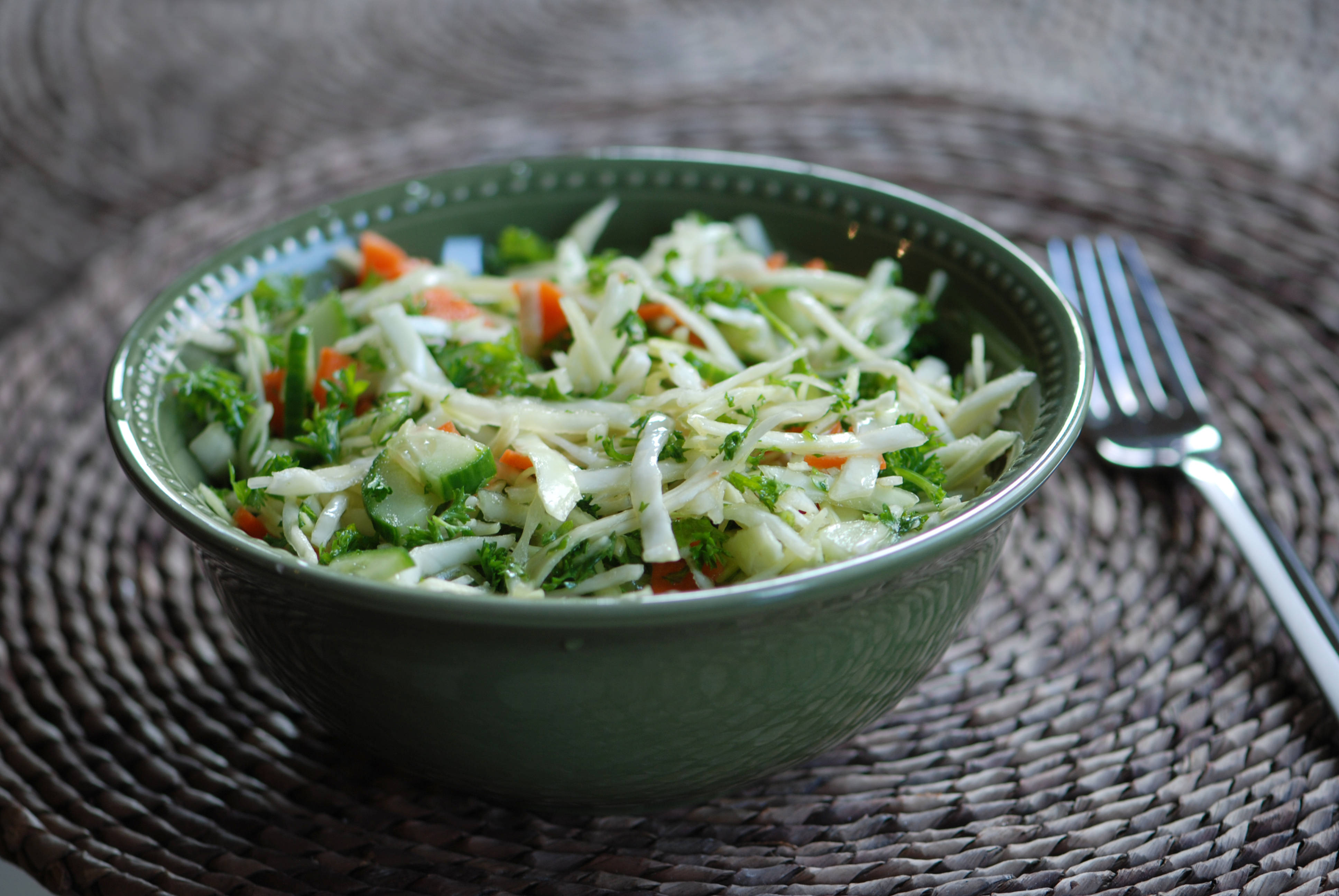 Weisskohlsalat mit Karotten, Gurken und Kräutern in Schüssel.