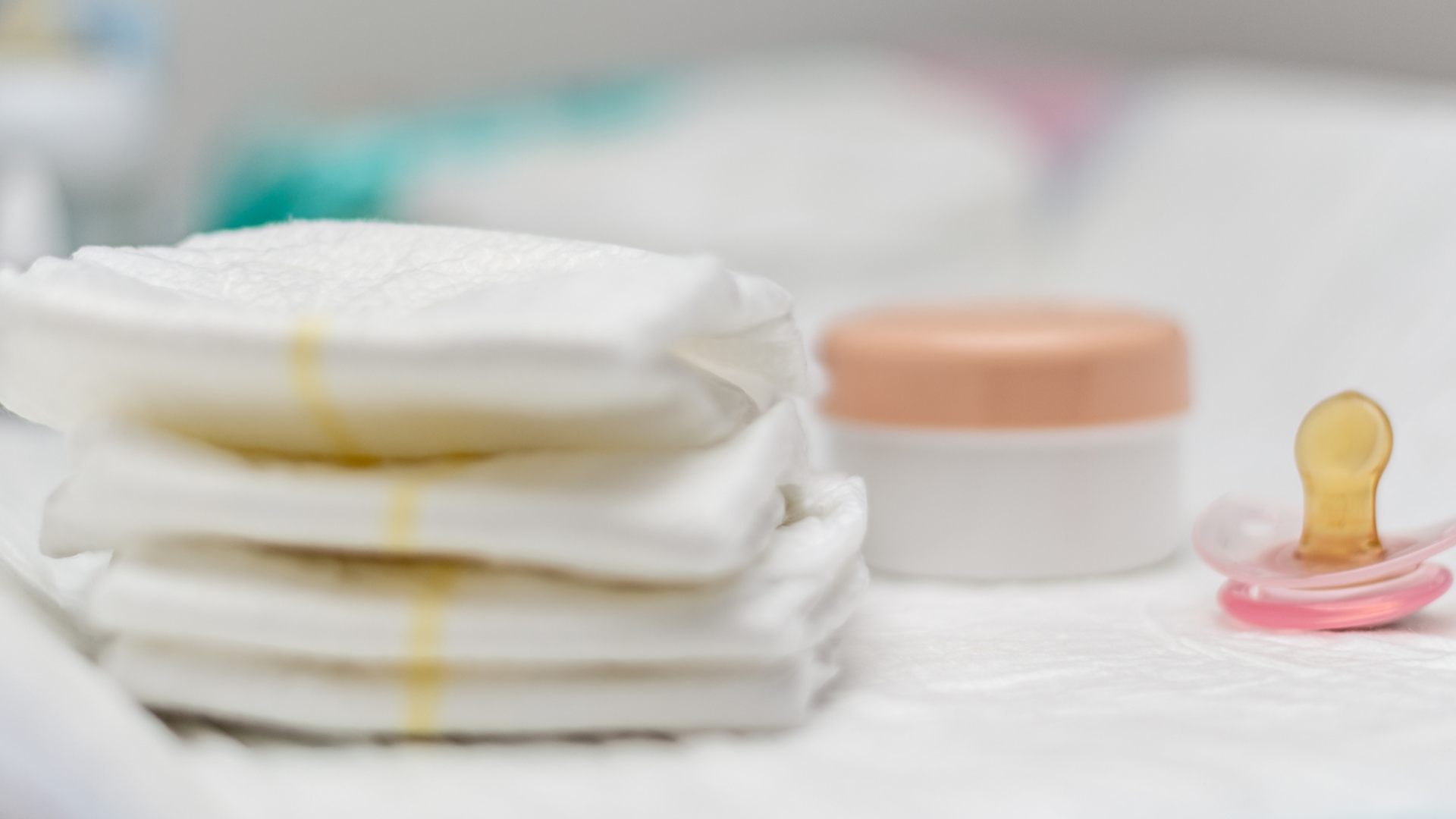 Stillleben mit Babypads, Creme und Schnuller.