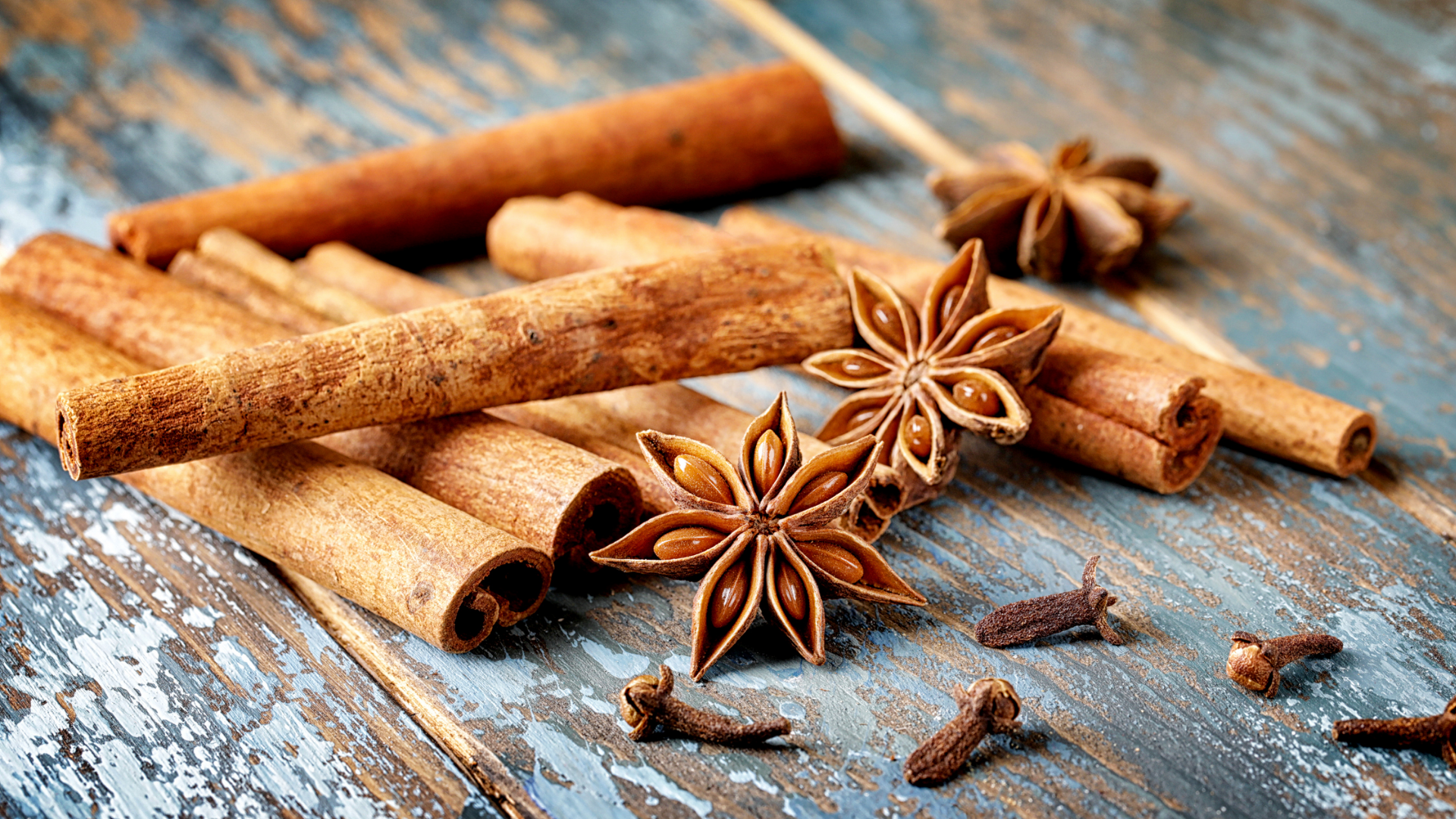 Zimtstangen, Sternanis und Nelken auf Holzuntergrund.