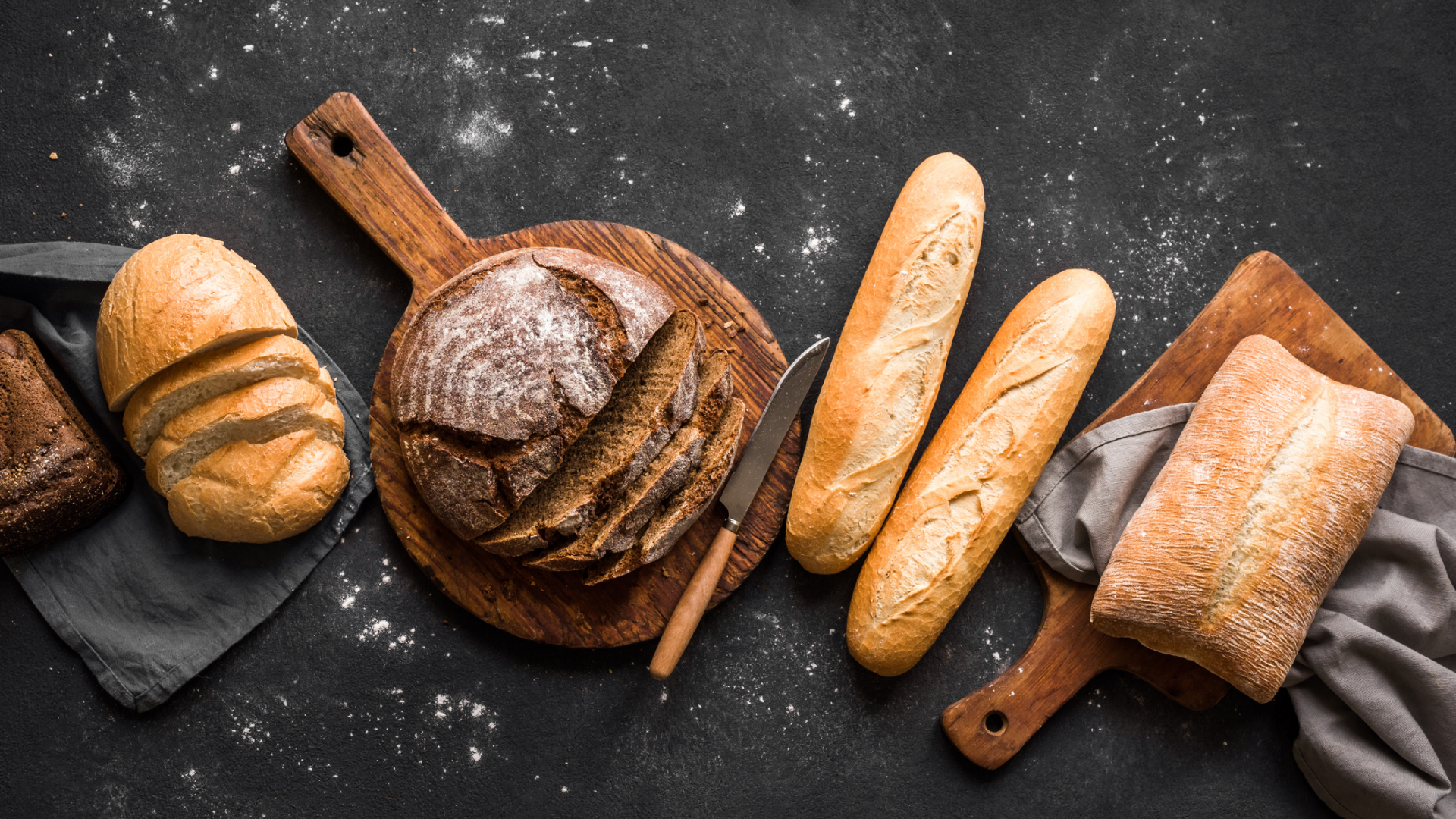 Verschiedene Brotsorten auf Holzbrettern mit Mehlstaub.