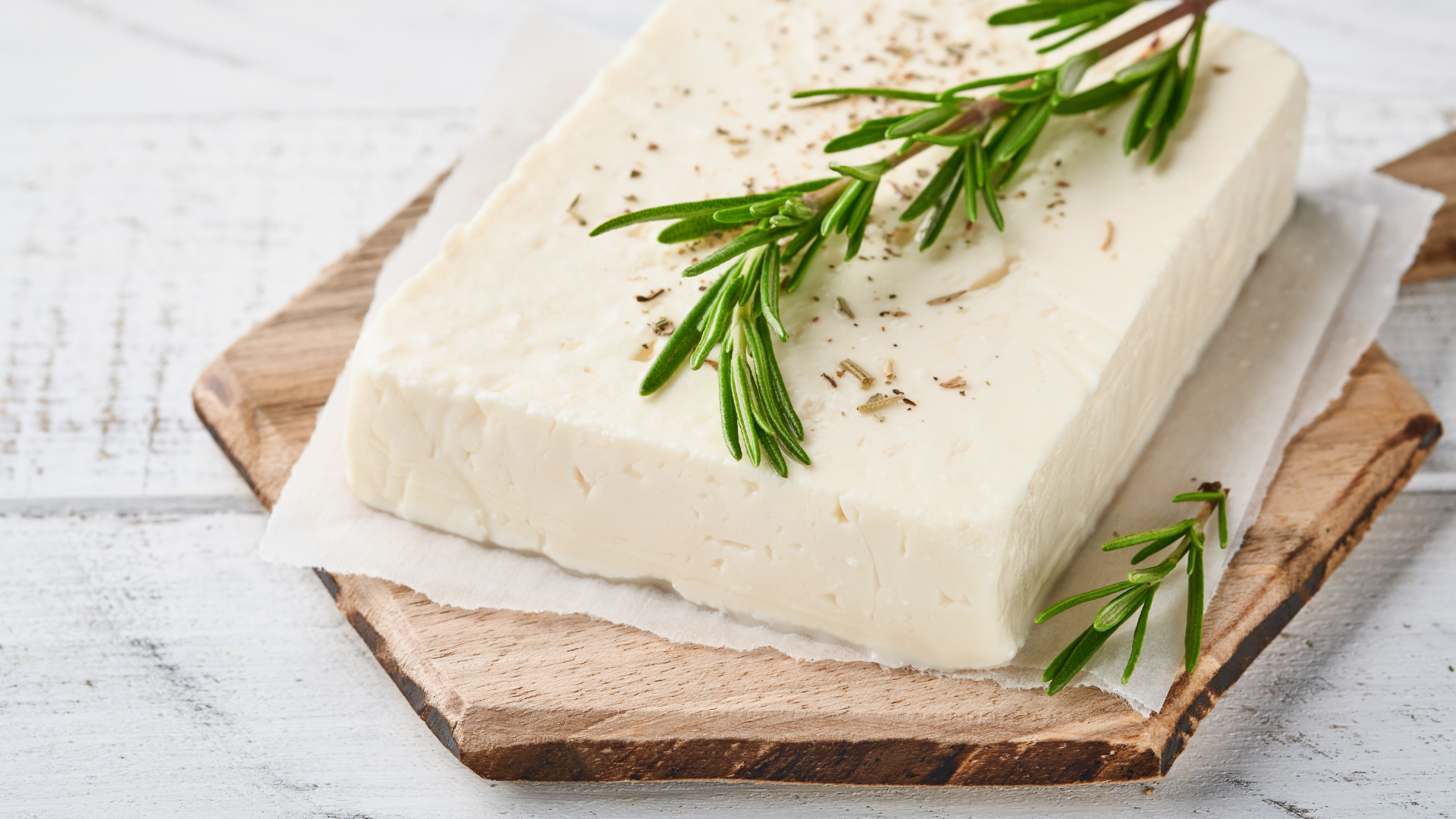 Feta-Käse mit Rosmarin auf Holzbrett.