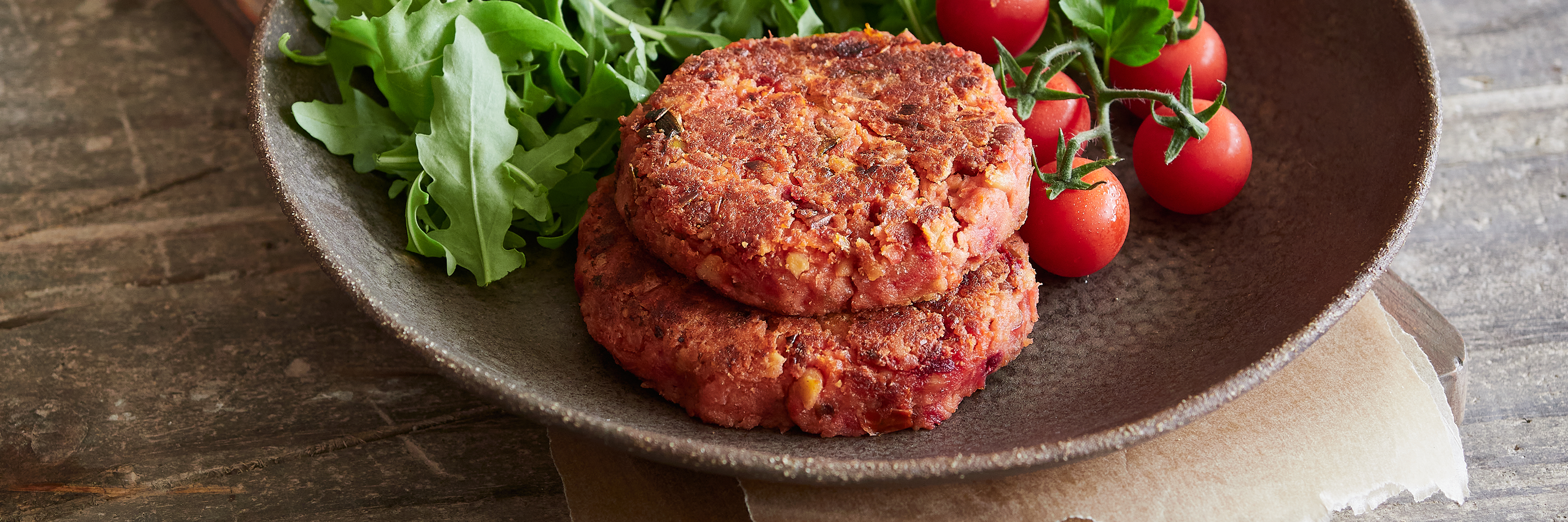 Gestapelte, gegrillte Fleischersatz-Burger mit Salz, einer halbiert.