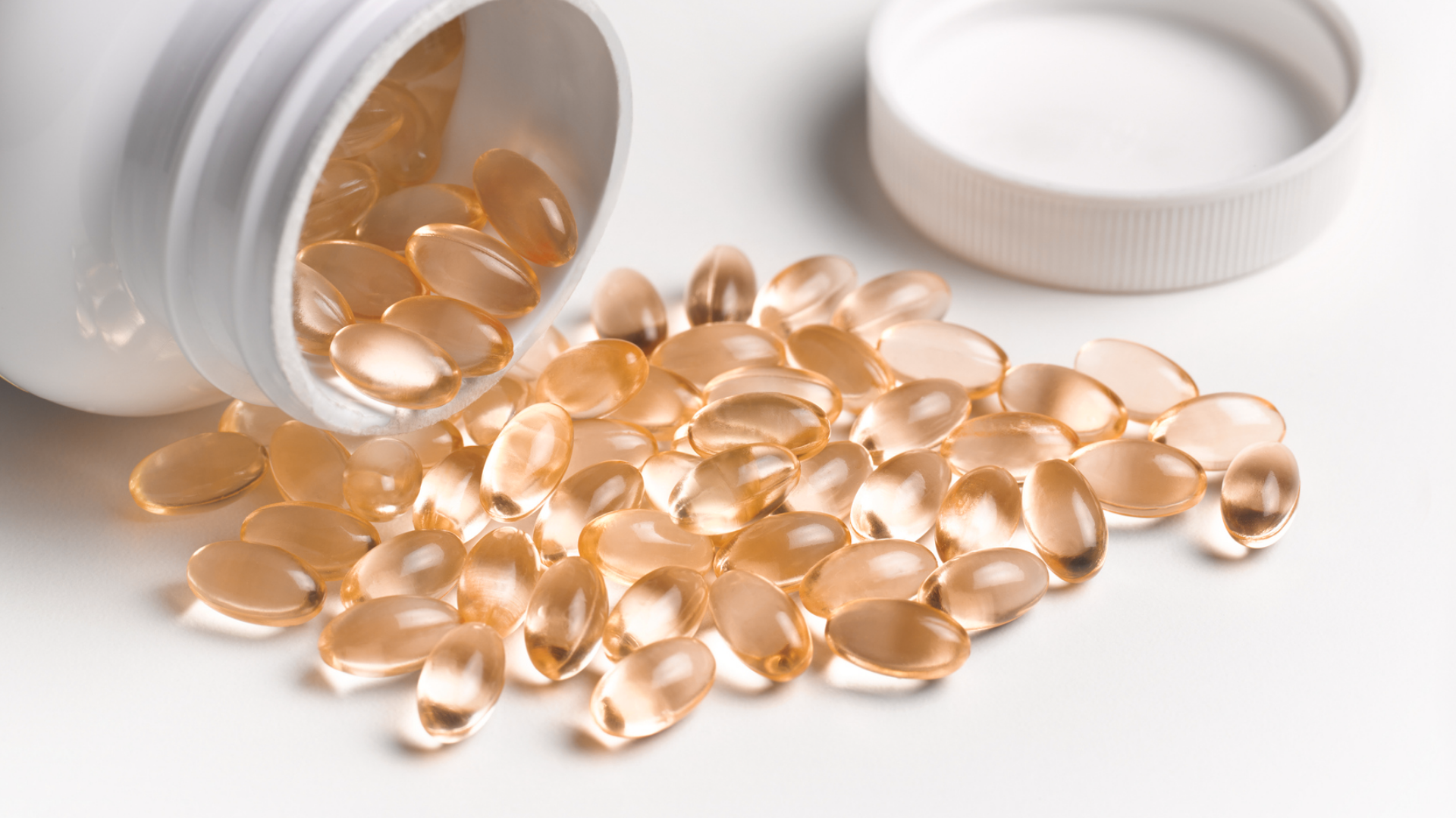 Kapseln laufen aus weißem Behälter, weißer Hintergrund.