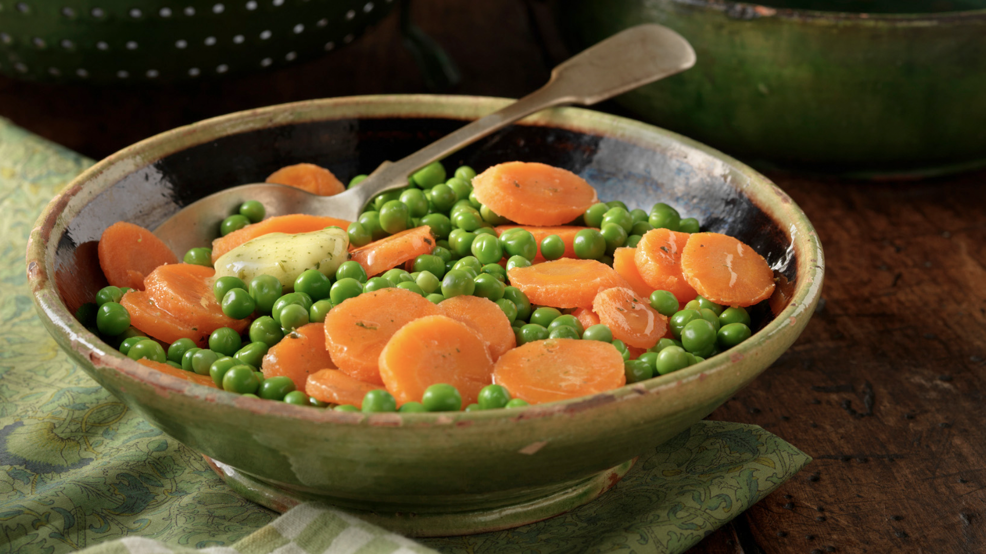 Schüssel mit Erbsen und Karotten, Löffel, Stoffserviette.