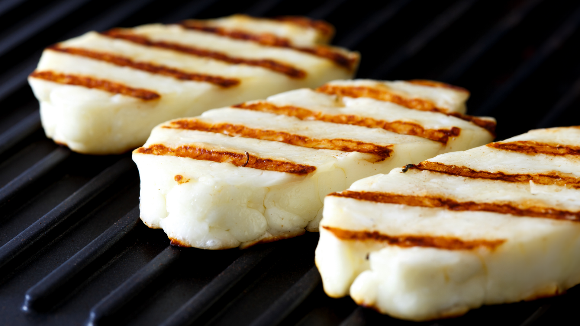 Gegrillter Halloumi-Käse mit Grillspuren auf einem Grillrost.