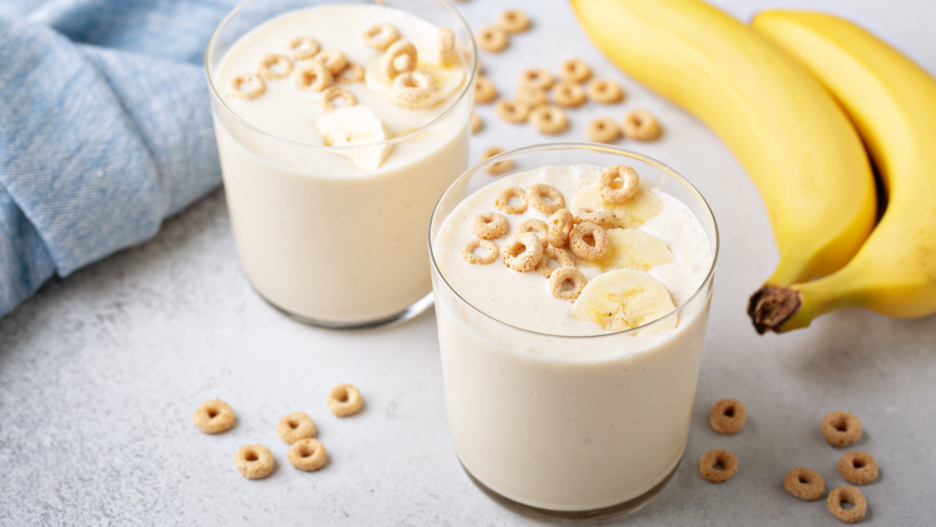 Zwei Gläser mit cremigem Inhalt, Bananen und Getreideringen.