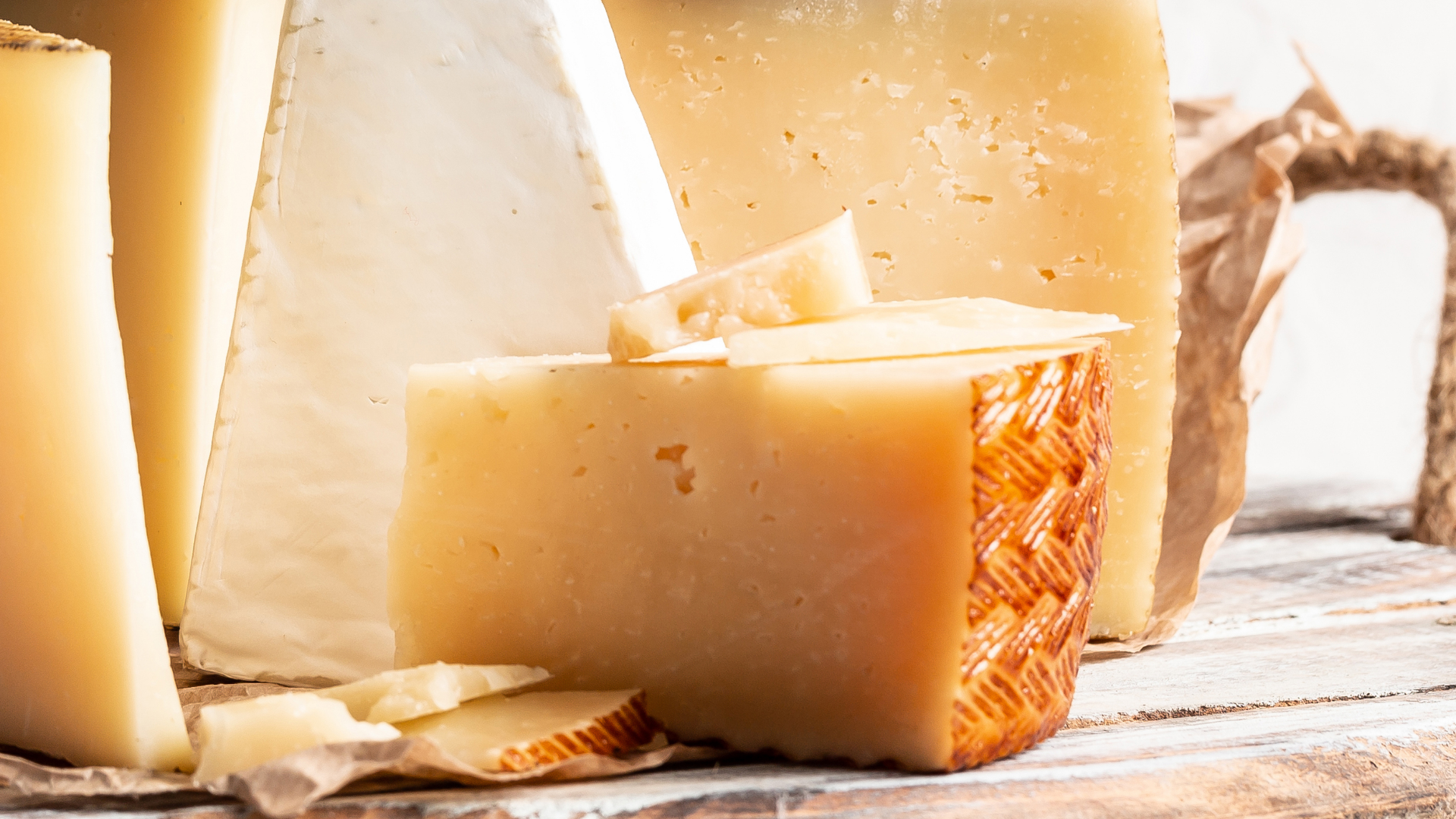 Verschiedene Käsesorten, Scheiben und Stücke auf Holzbrett.