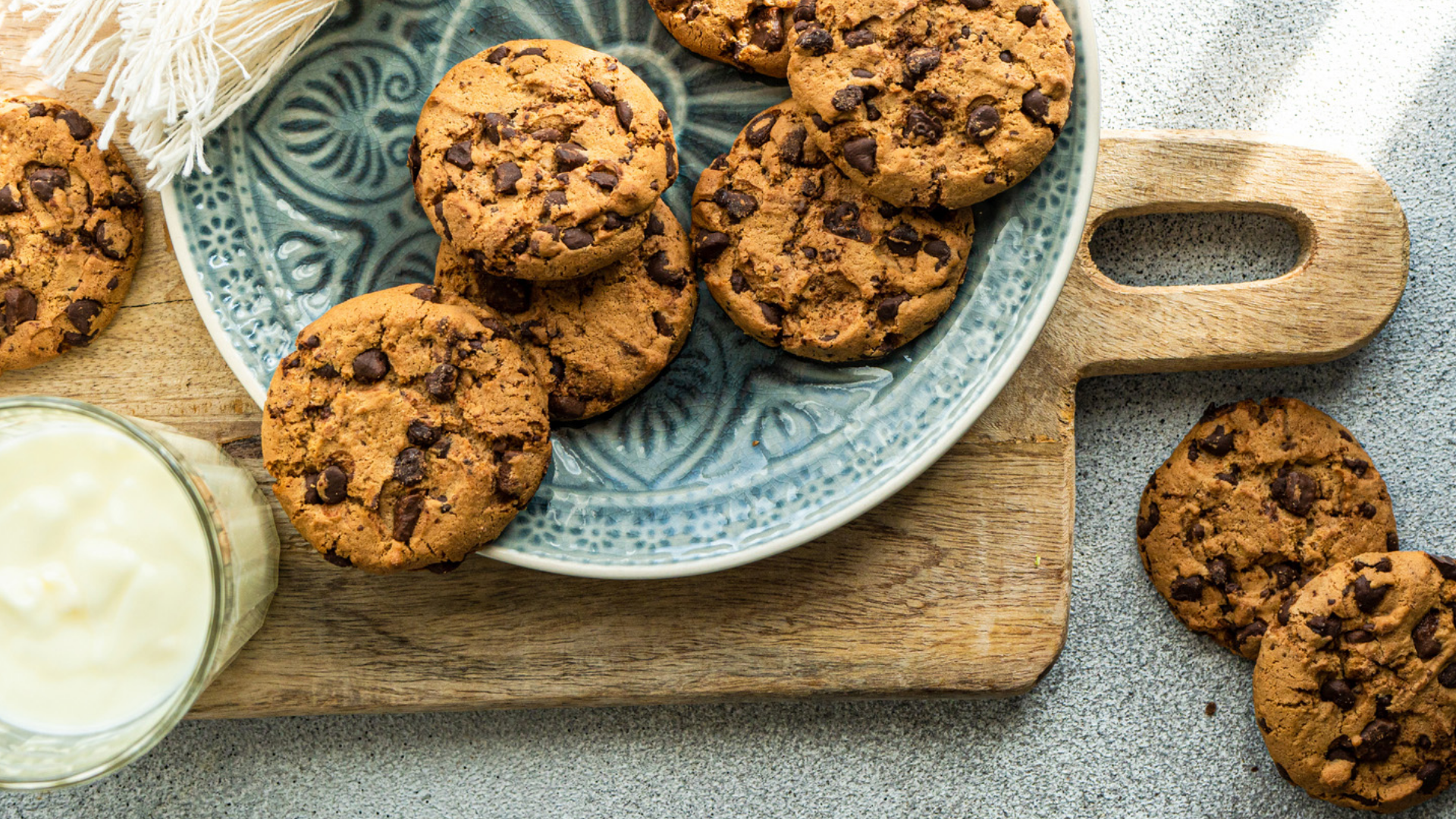 Schokoladenkekse auf Teller und Holzbrett mit Milch.