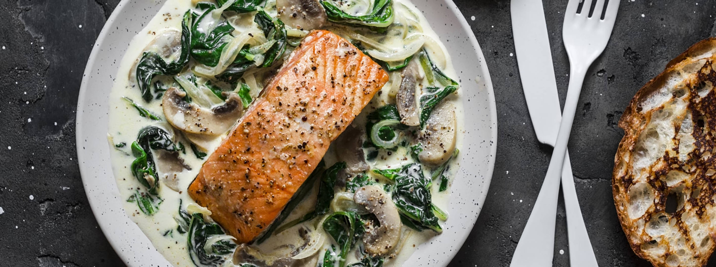 Gebratener Lachs mit Rahmspinat und Pilzen.