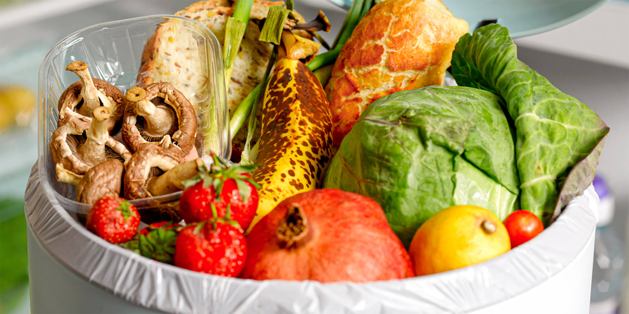 Ein Mülleimer ist stark befüllt mit noch essbarem Obst und Gemüse.