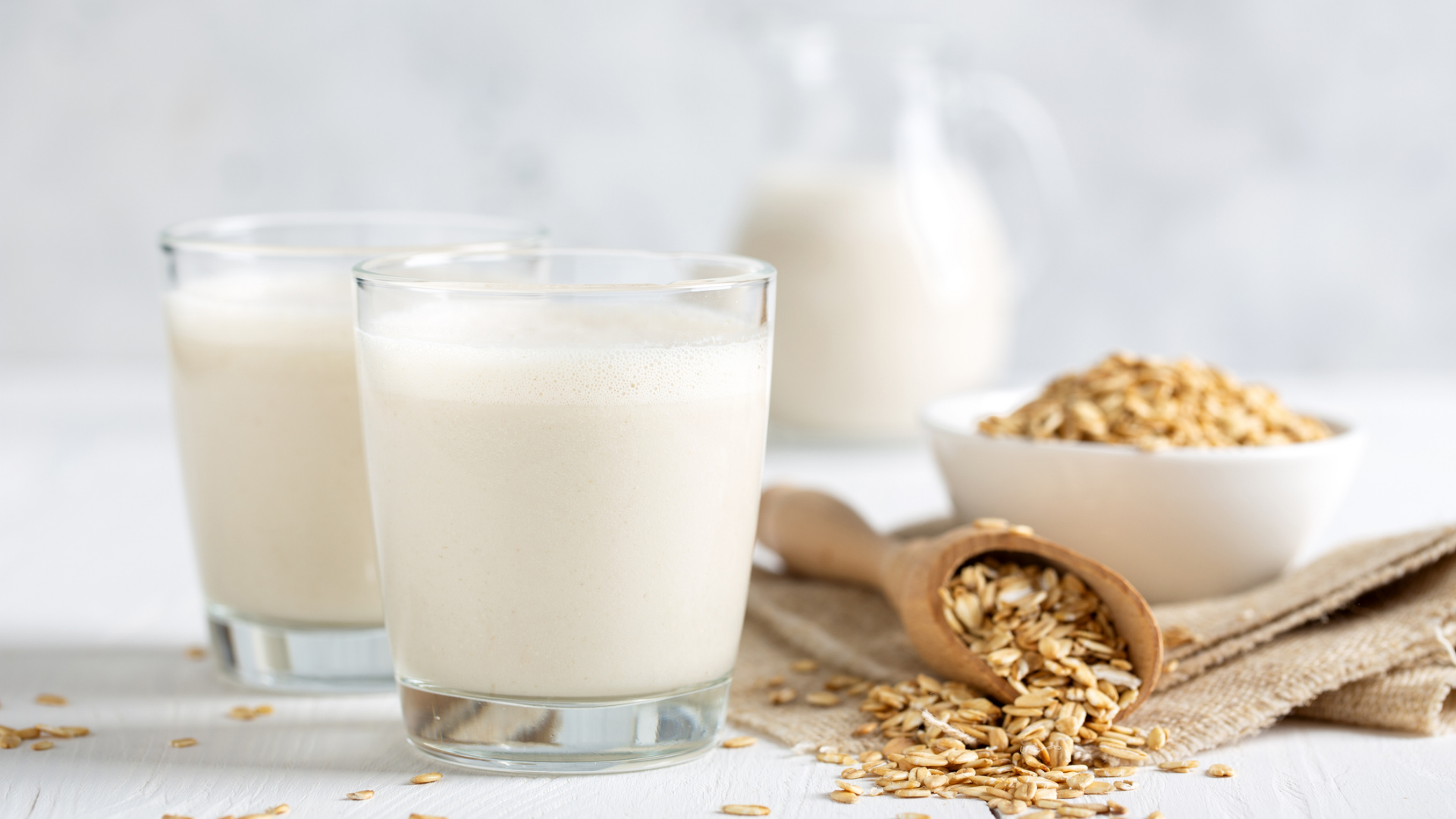 Zwei Gläser Hafermilch mit Haferflocken und Schale.