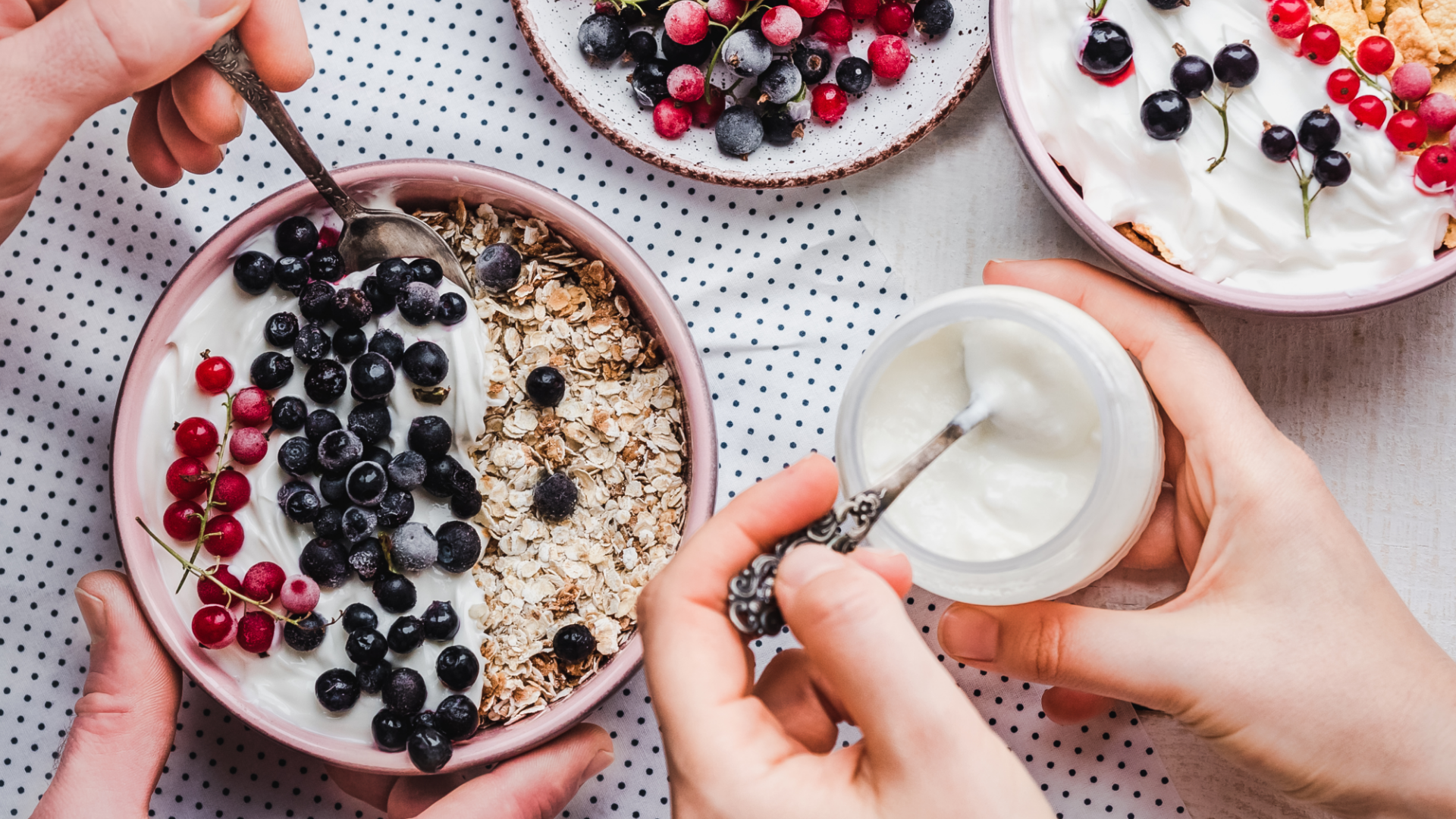 Hände essen Joghurt mit Beeren und Müsli.