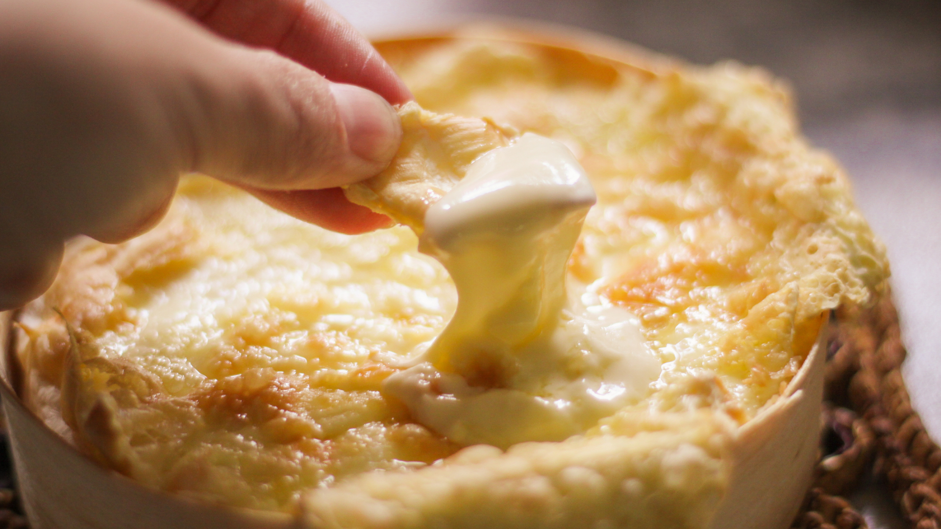 Ofenkäse mit schmelzendem Käse und Hand mit Cracker.