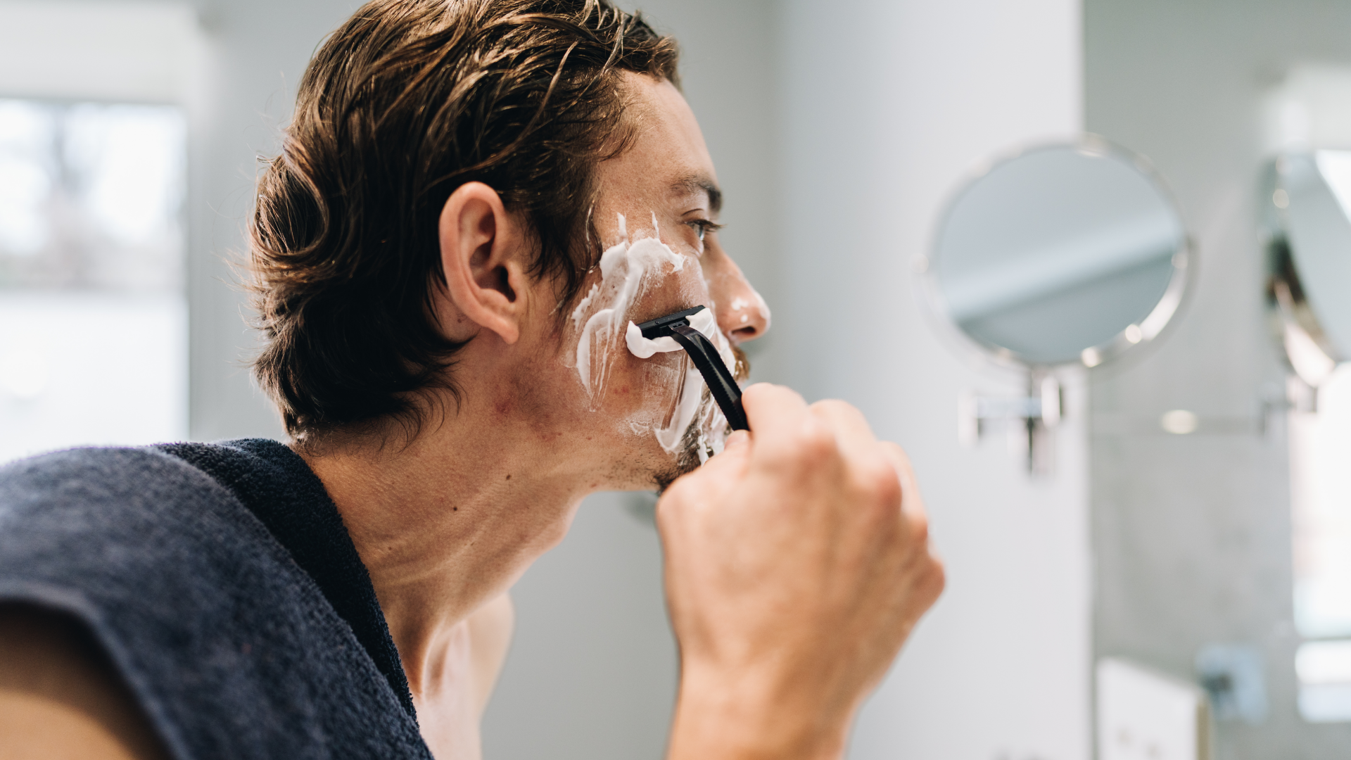 Mann rasiert sich mit Rasierschaum und Rasierer.