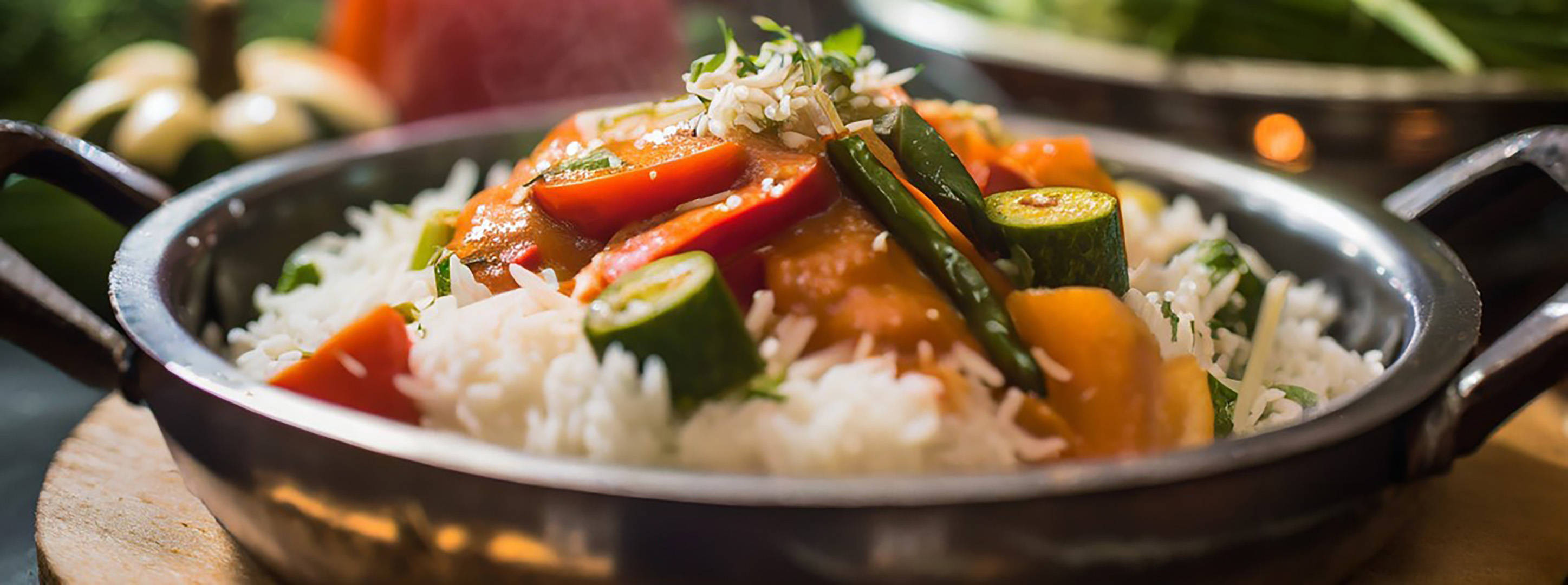 Dampfendes Reisgericht mit Gemüse, Sauce und Kräutern.