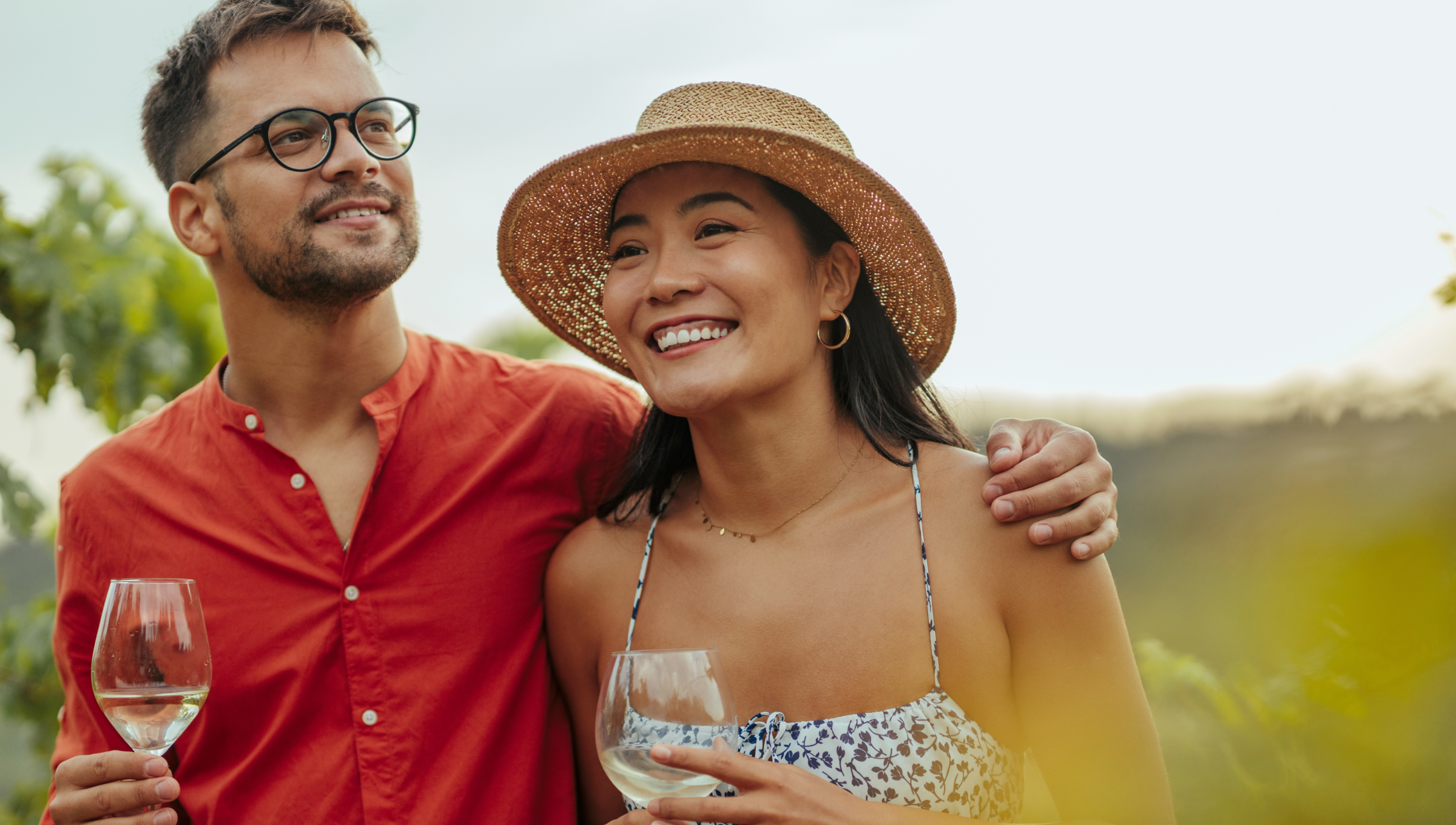 Ein Paar mit Weinglas in der Hand steht in den Weinbergen.