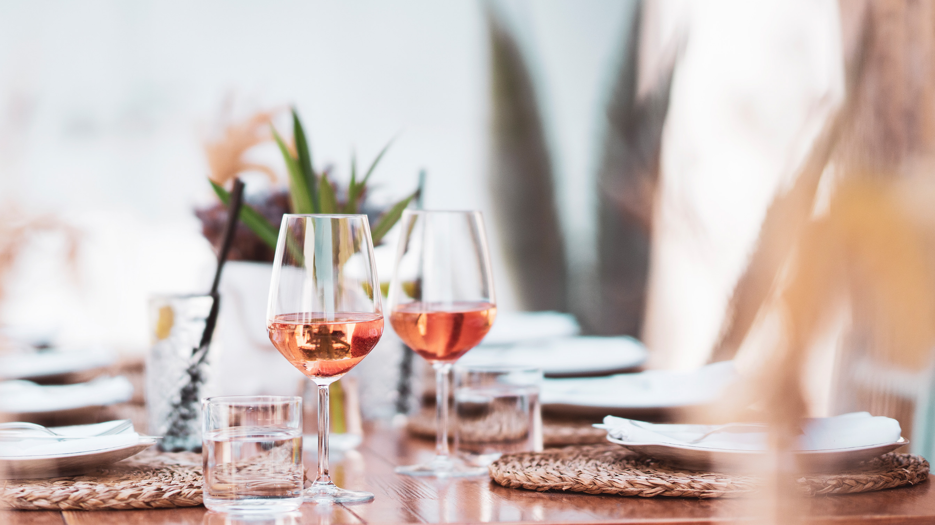 Gedeckter Tisch mit Roséwein in Gläsern und Wassergläsern.