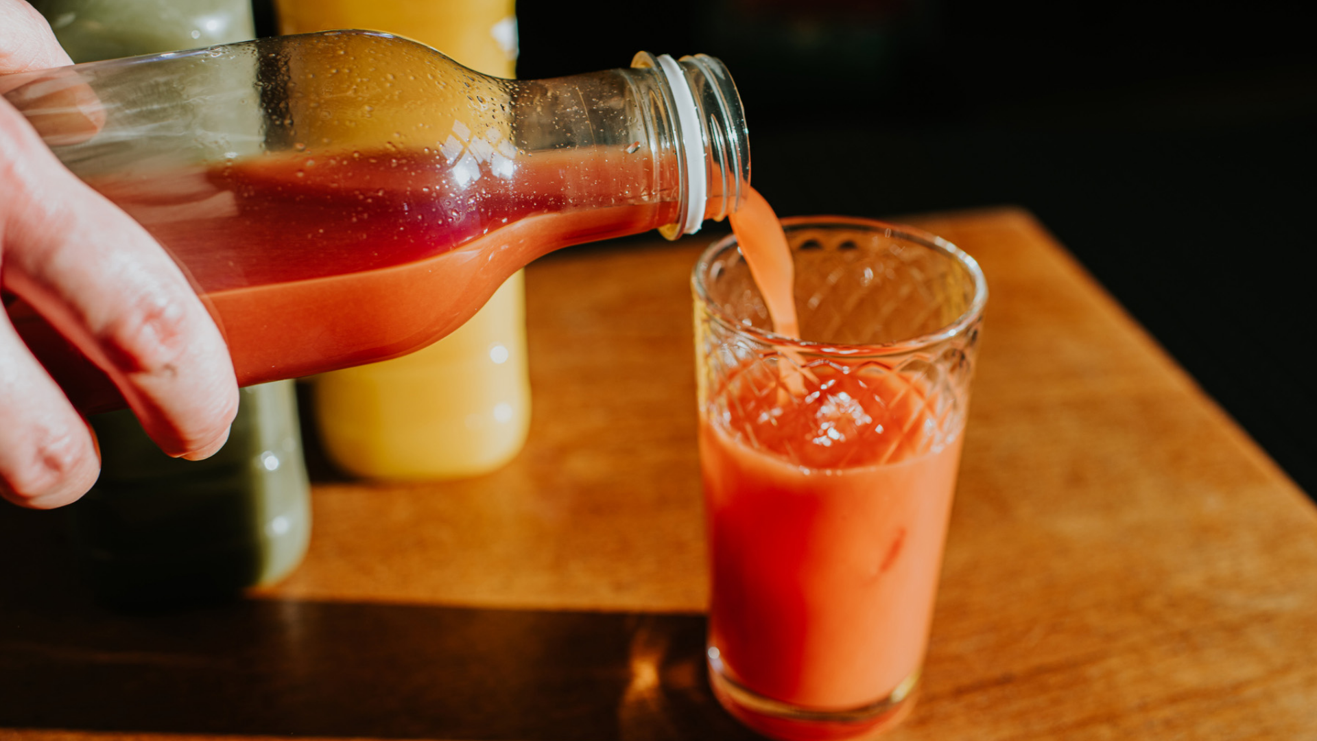 Saft wird aus einer Flasche in ein Glas gegossen.