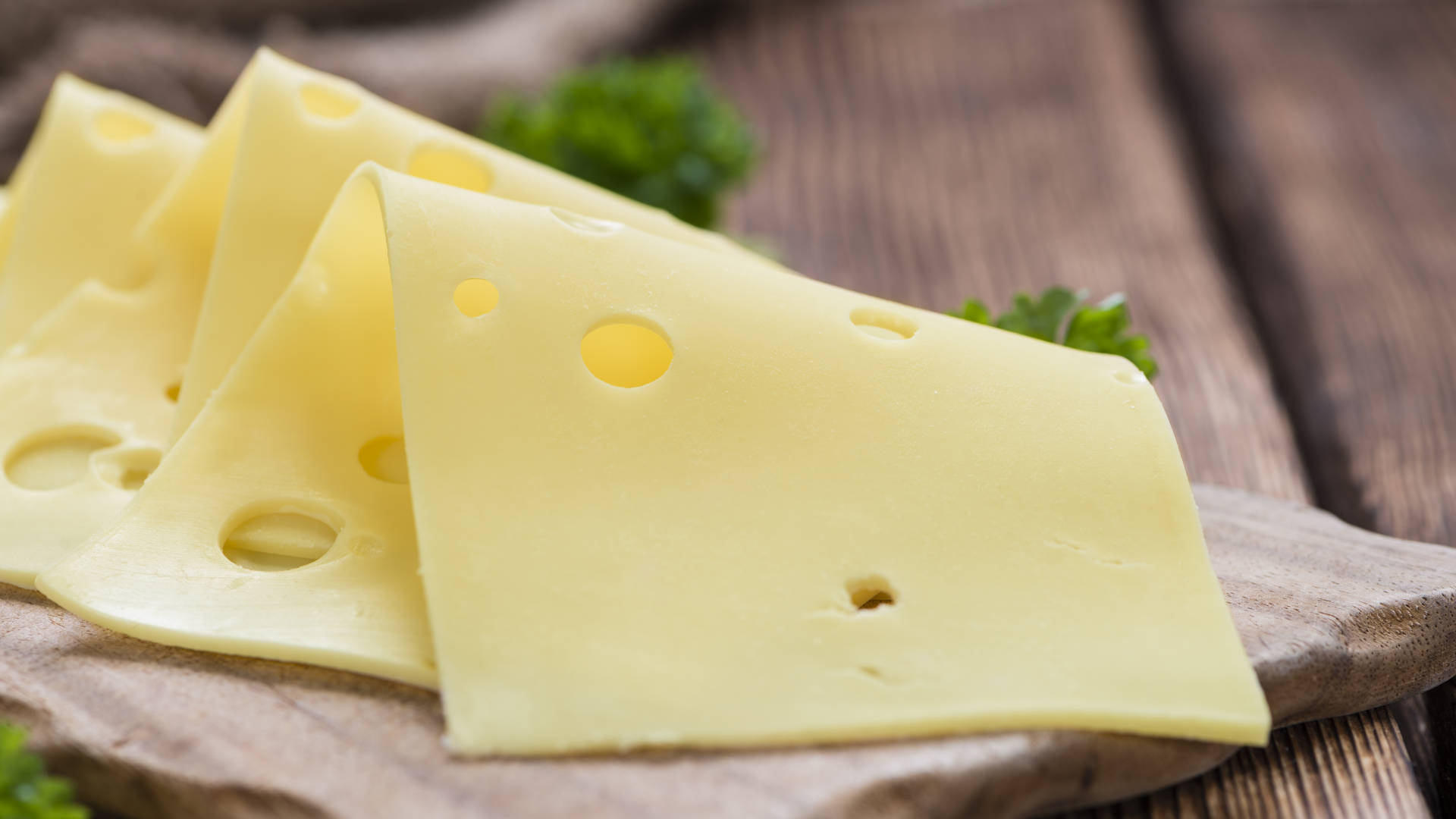 Käsescheiben mit Löchern auf Holzbrett, Petersilie.