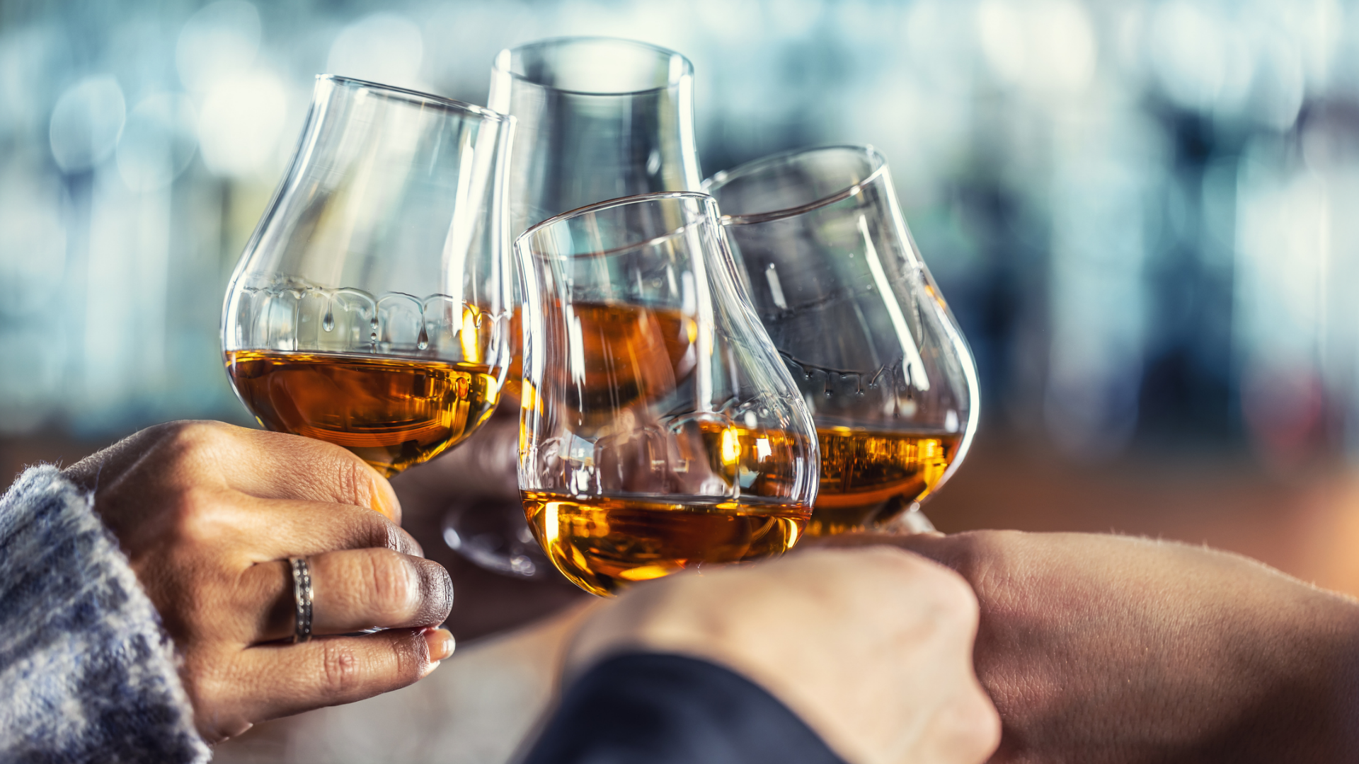 Anstoßende Gläser mit bernsteinfarbenem Getränk in Händen.
