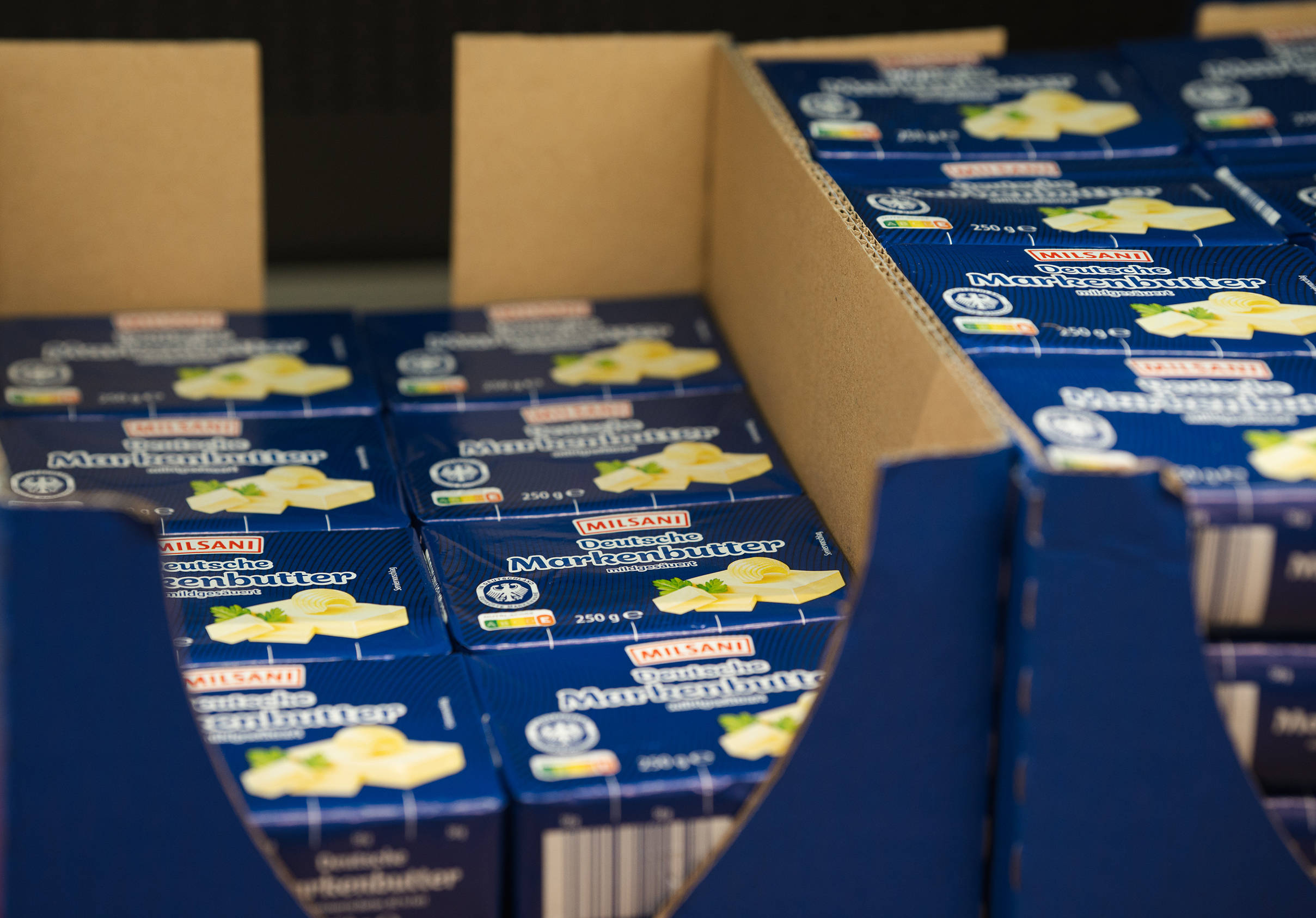 Nahaufnahme mehrerer Packungen ALDI Milsani Deutsche Markenbutter in einem Karton im ALDI-Regal.