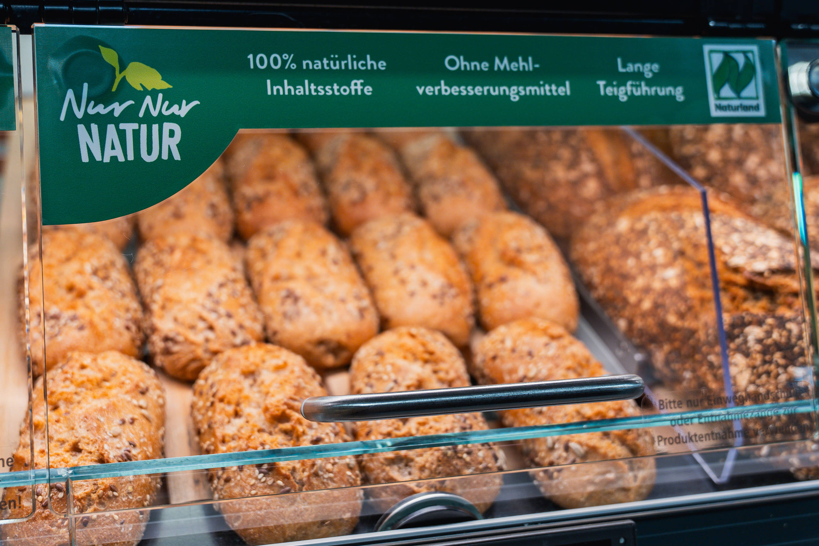 Auslage einer Brottheke in einer Aldi Süd Filliale, mit verschiedenen Broten und Brötchen der Marke Nur Nur Natur.