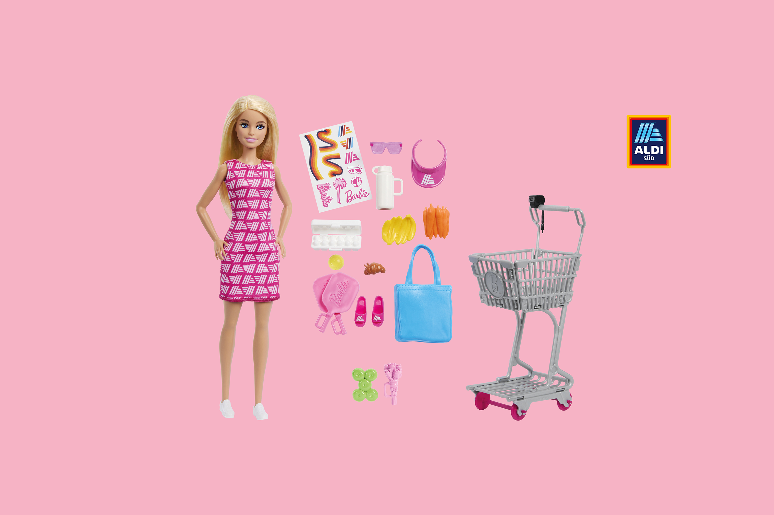ALDImania Barbie® mit Einkaufswagen und verschiedenen Accessoires auf pinken Hintergrund.