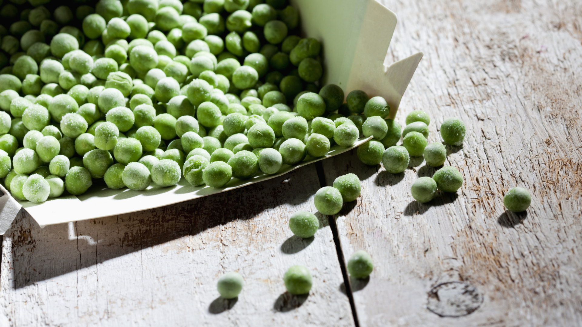 Gefrorene Erbsen in Verpackung auf Holzoberfläche.