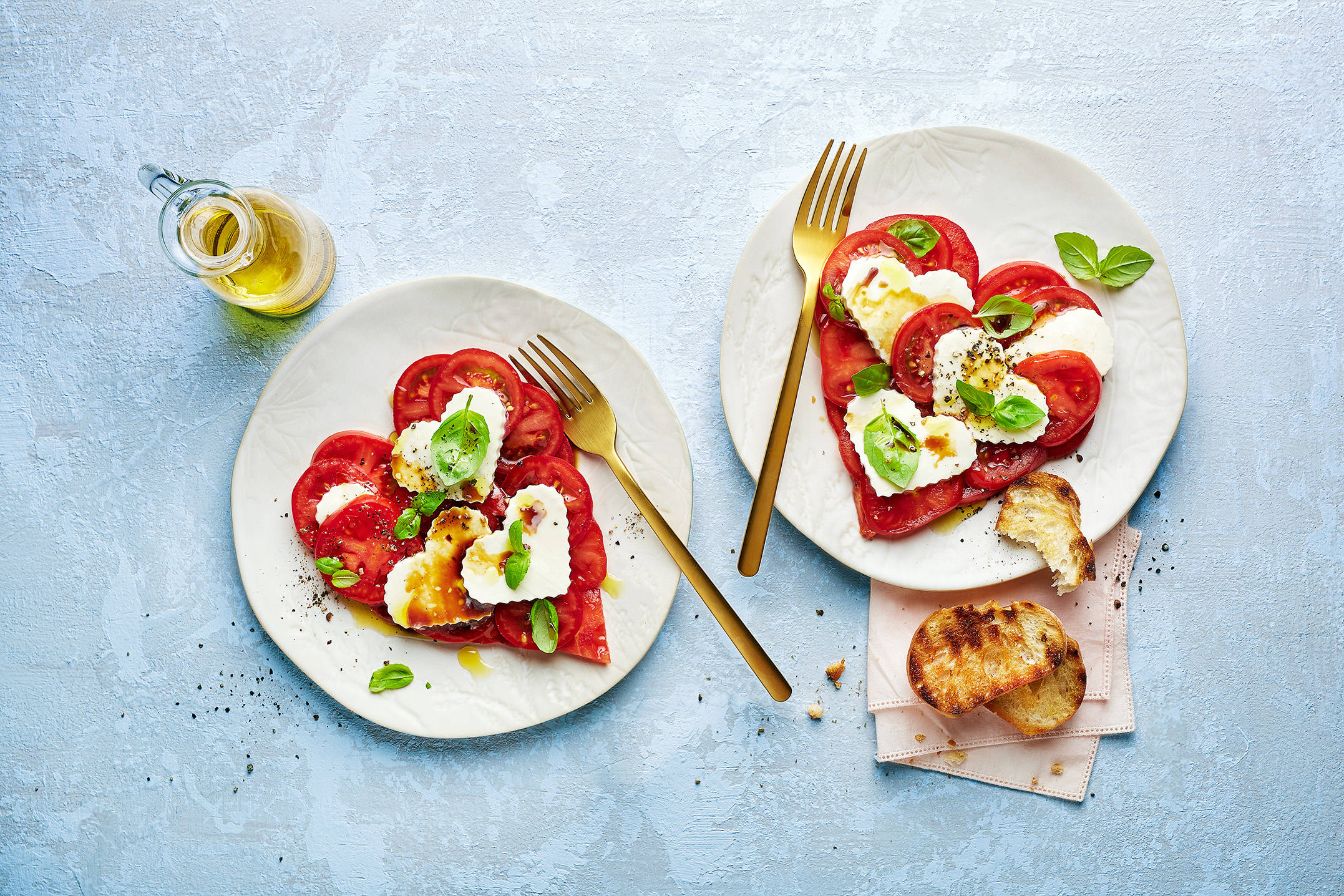 Zwei herzförmige Caprese-Salate mit Tomaten, Mozzarella, Basilikum.