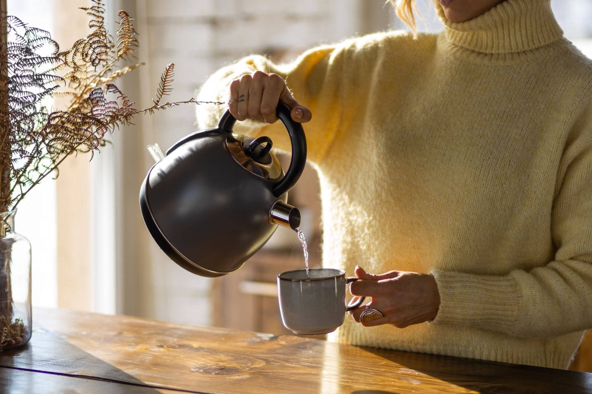 Eine Frau schenkt sich heißes Wasser in eine Tasse.