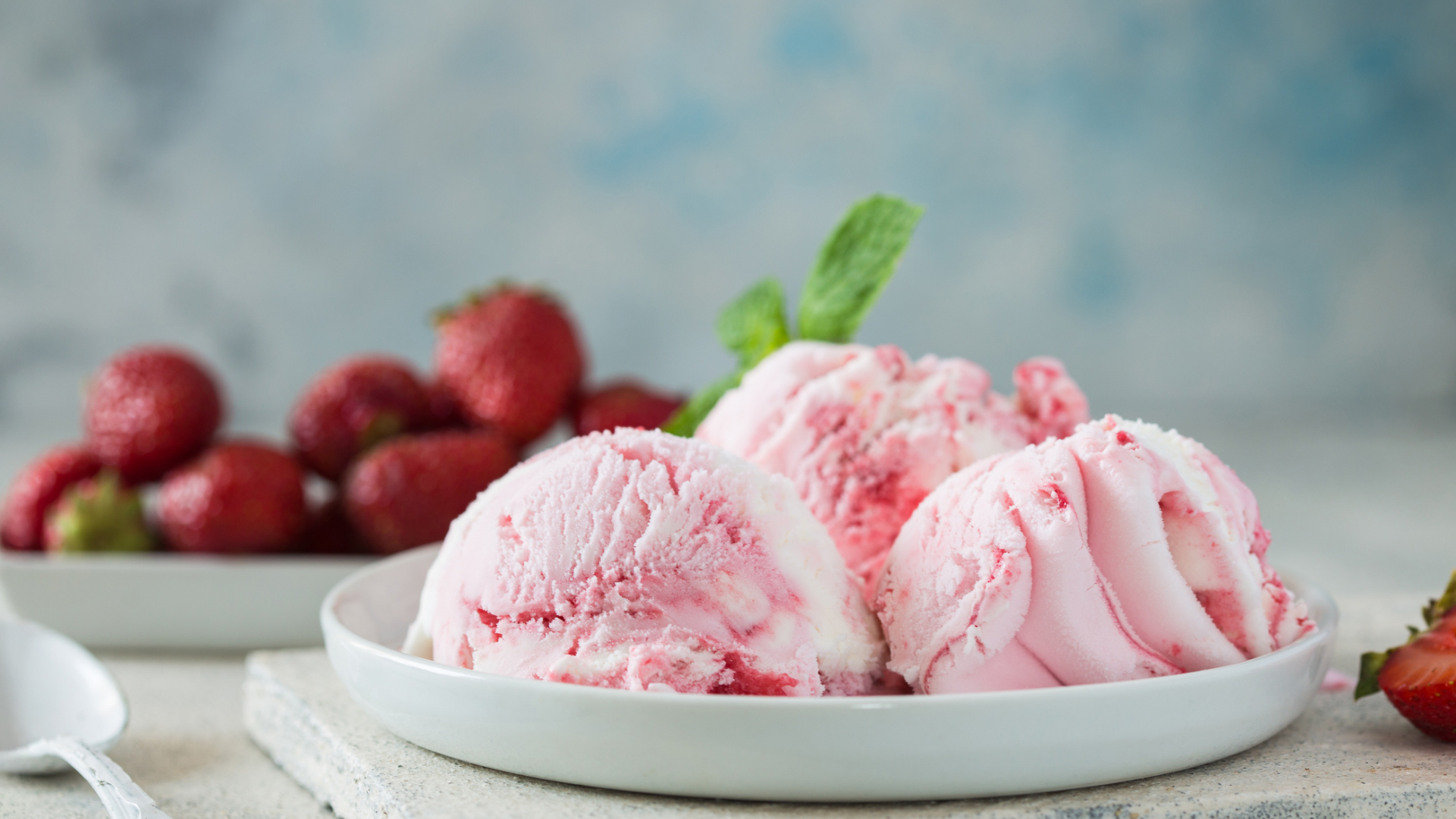Erdbeereis mit frischen Erdbeeren und Minze auf Tellern.