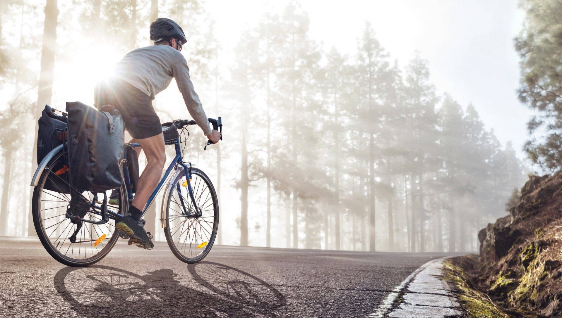 Ein Mann fährt auf einer Straße mit einem Rennrad, bestückt mit Fahrradtaschen.