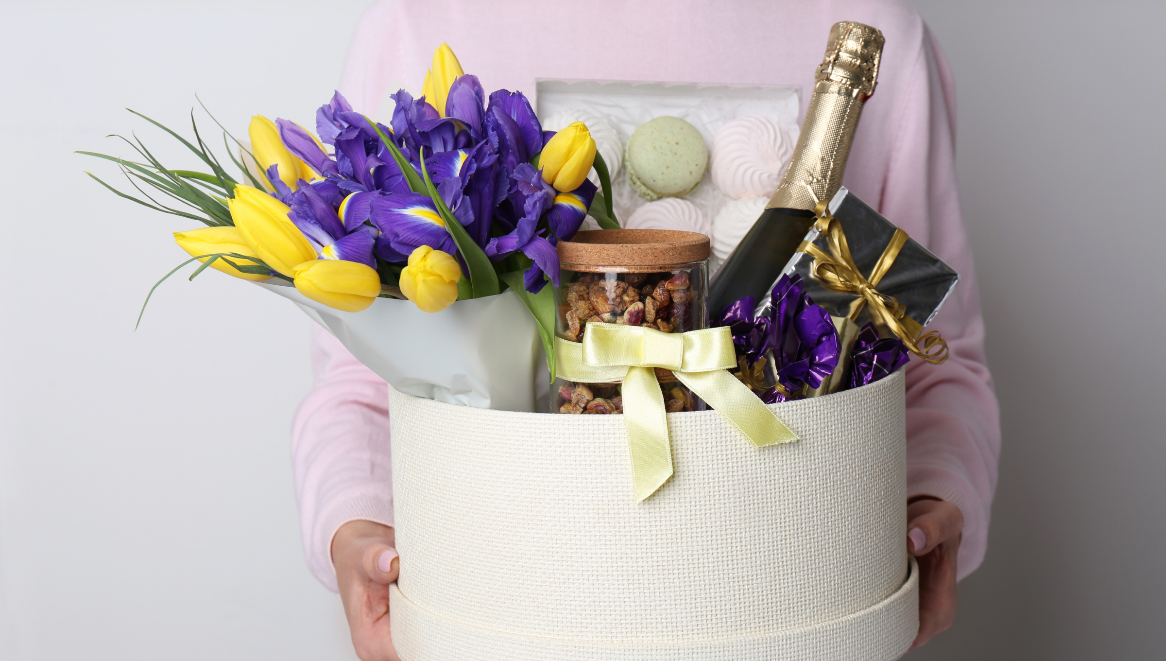 Geschenkkorb mit Blumen, Sekt, Nüssen und Süßigkeiten.