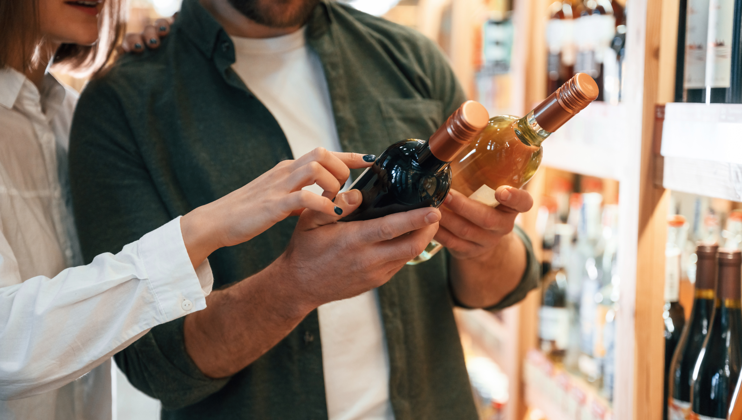 Eine Frau und Mann lesen Etiketten auf Weinflaschen.