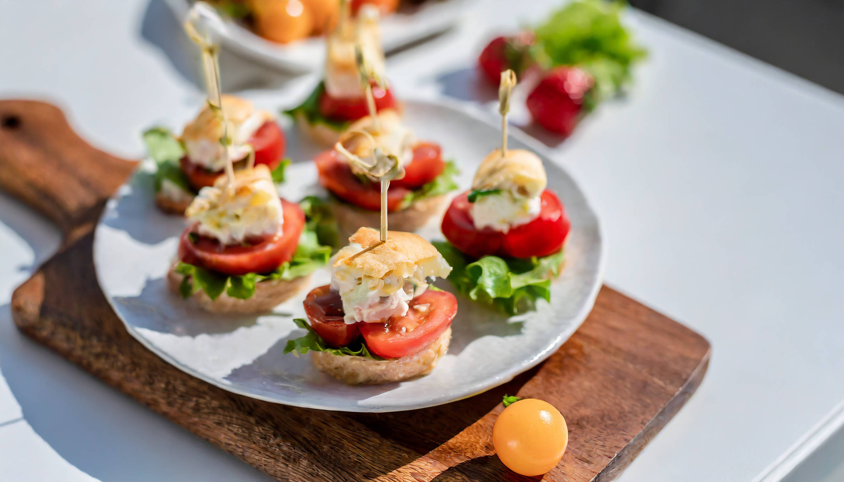 Kleine Häppchen mit Tomate, Salat und Gebäck auf Teller.