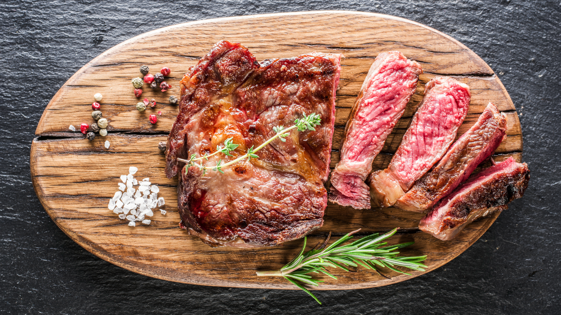 Gegrilltes Rindersteak mit Rosmarin und Gewürzen auf Holzbrett.