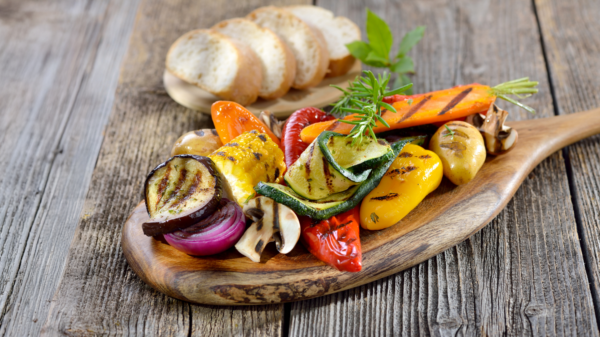 Gegrilltes Gemüse und Brot auf Holzbrett.