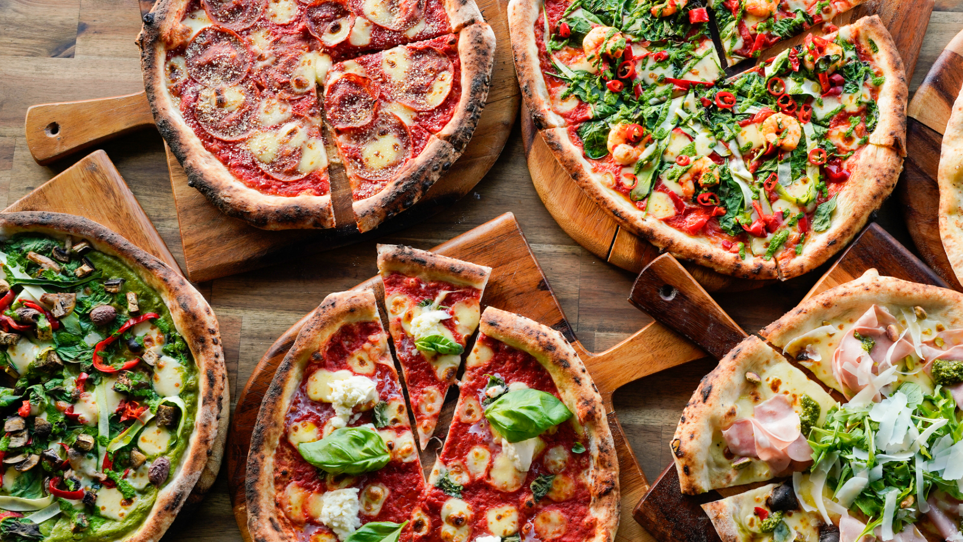 Verschiedene Pizzas auf Holzbrettern, Ansicht von oben.