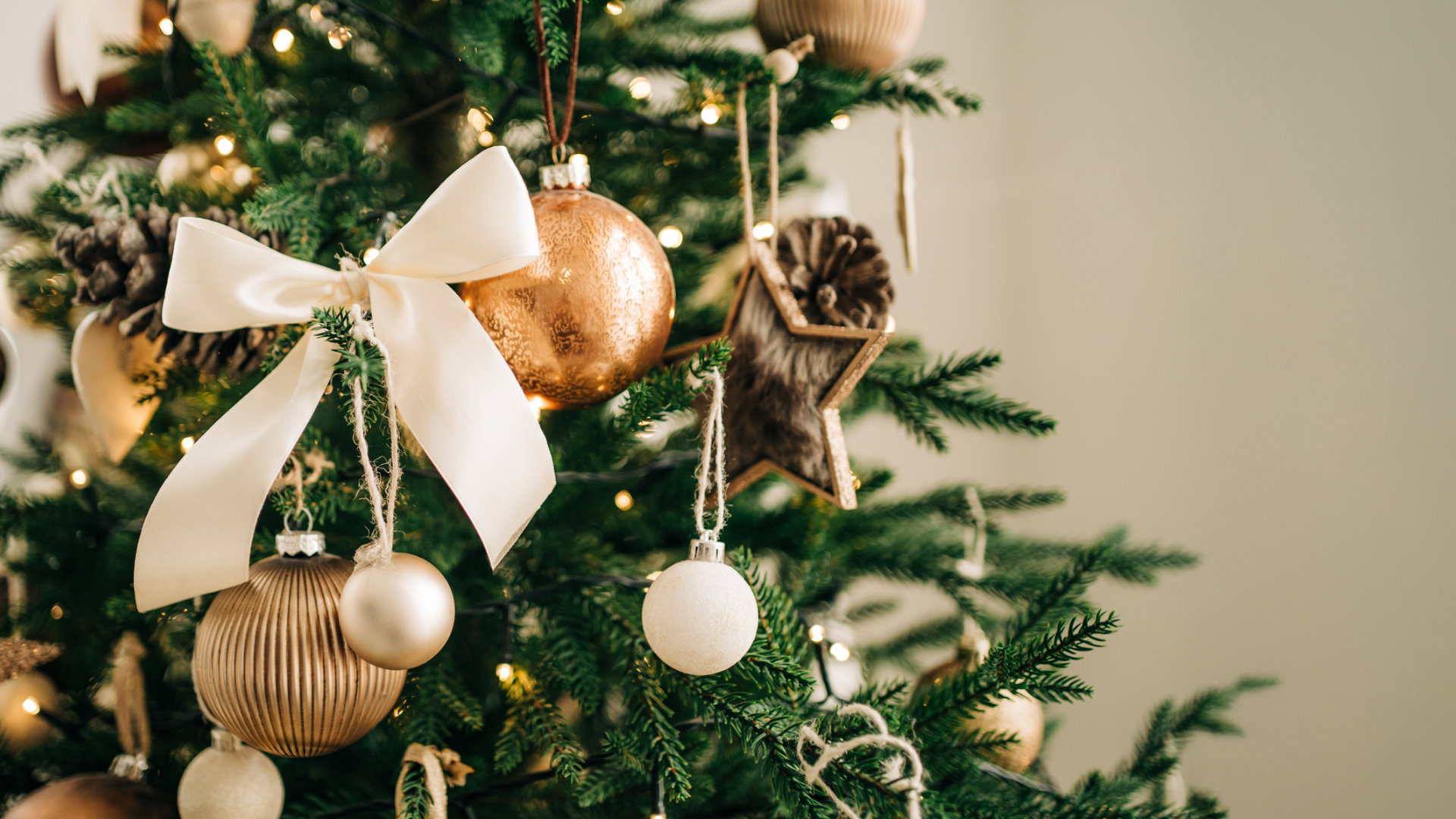 Geschmückter Weihnachtsbaum mit Schleife und Kugeln in Goldtönen.